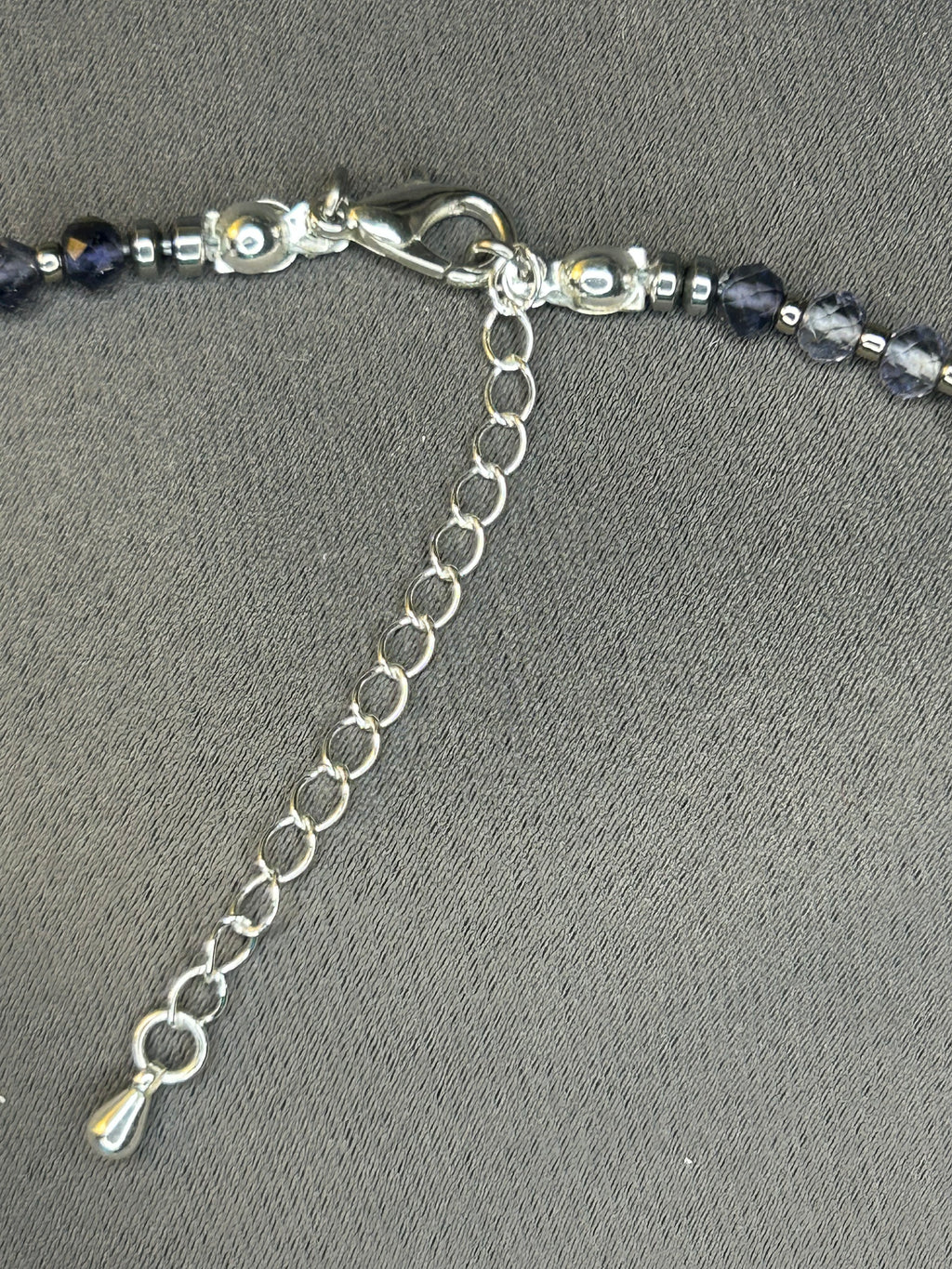 Necklace with blue beads and silver chain on a gray background