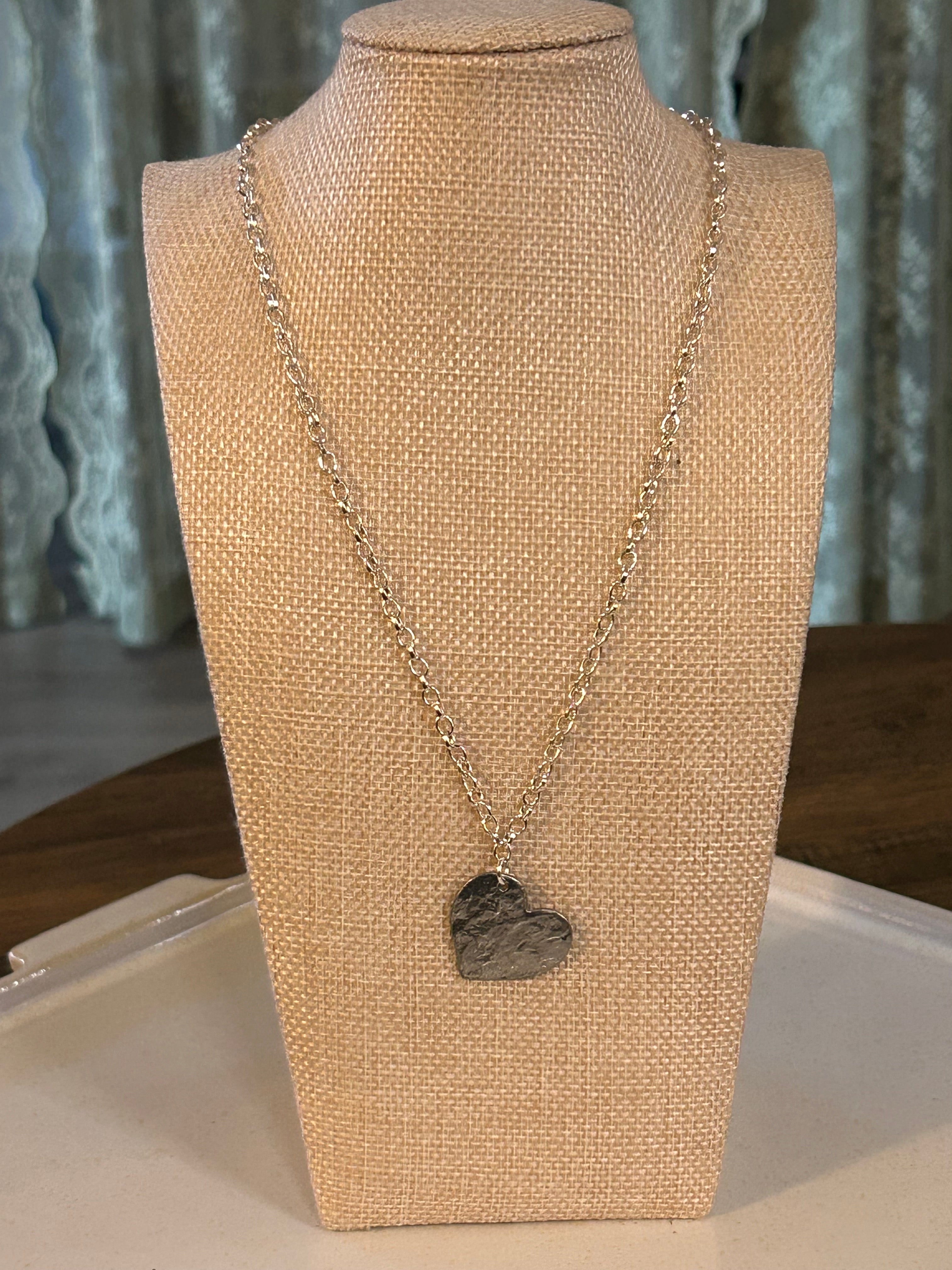 Necklace with a heart-shaped pendant on a mannequin bust.