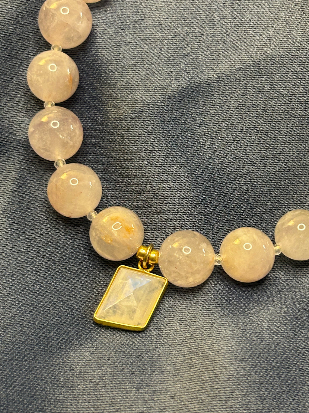 Necklace with purple beads and a gold clasp on a gray fabric background