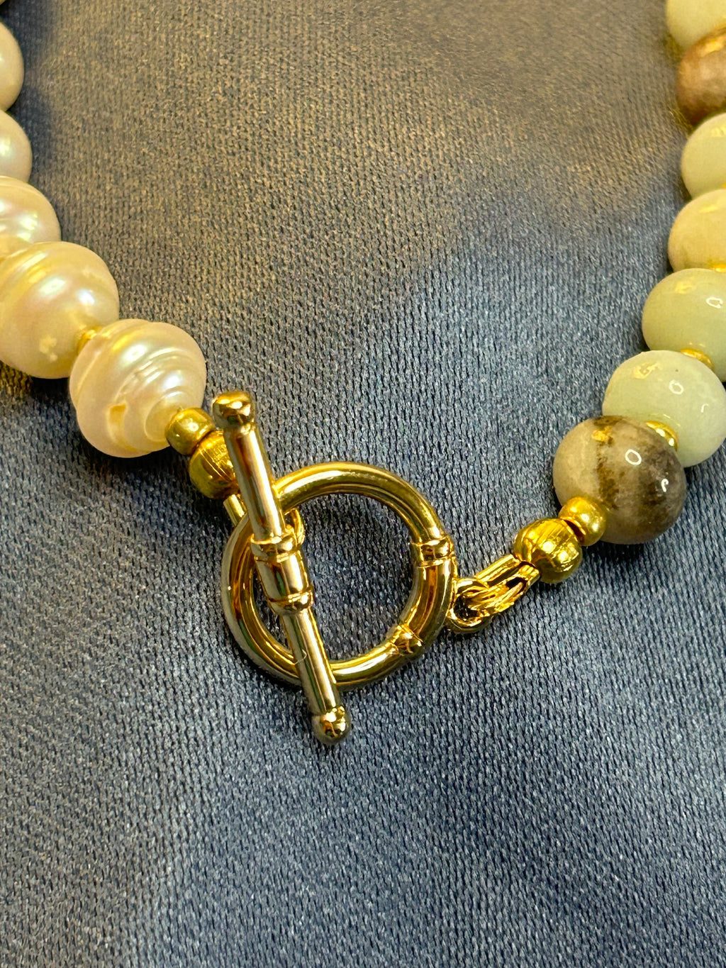 Close-up of a beaded necklace with a gold clasp on a textured gray background