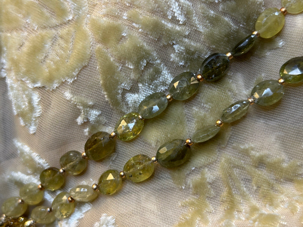 Necklace with green beads on a textured fabric background