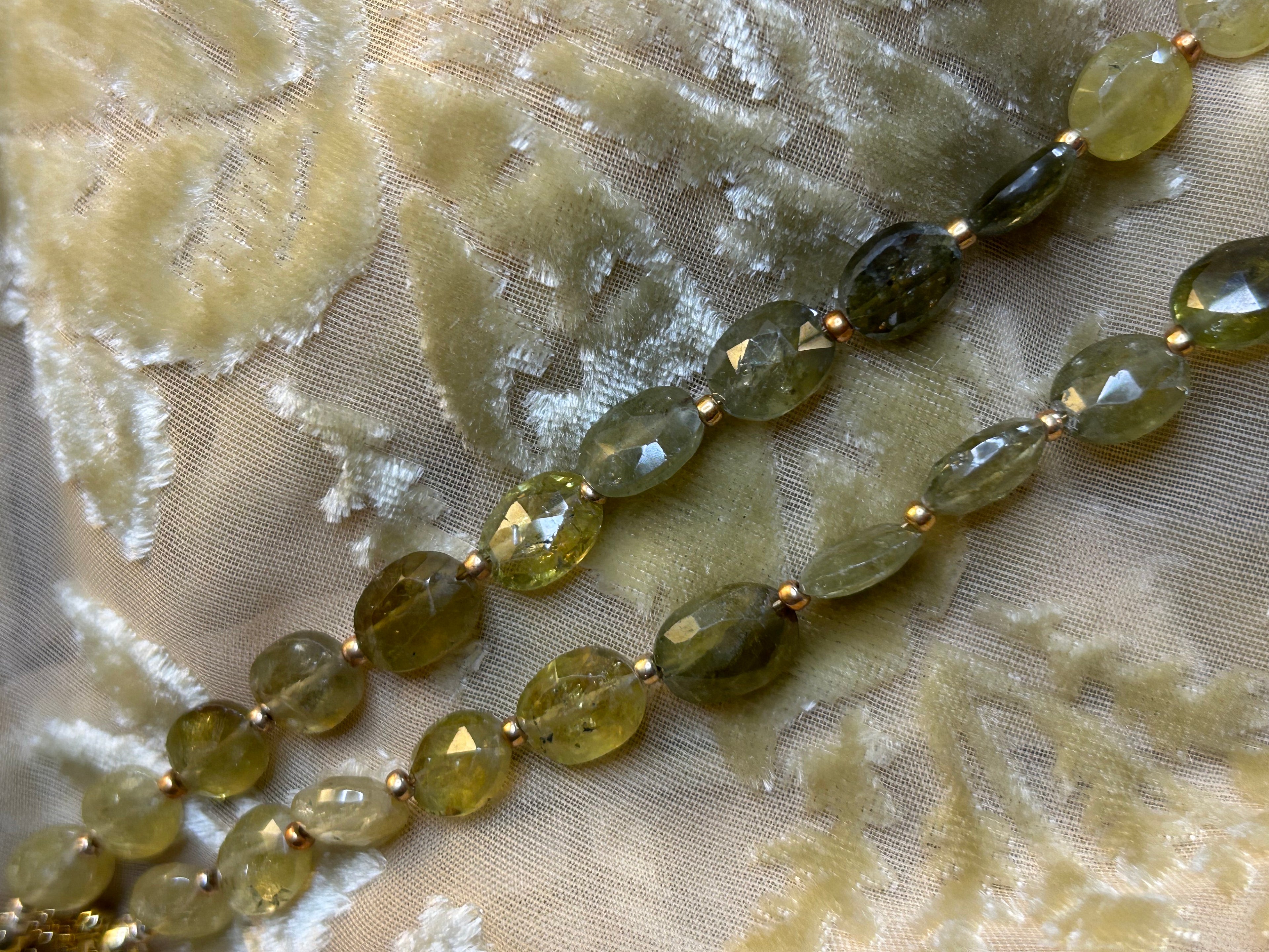 Necklace with green beads on a textured fabric background