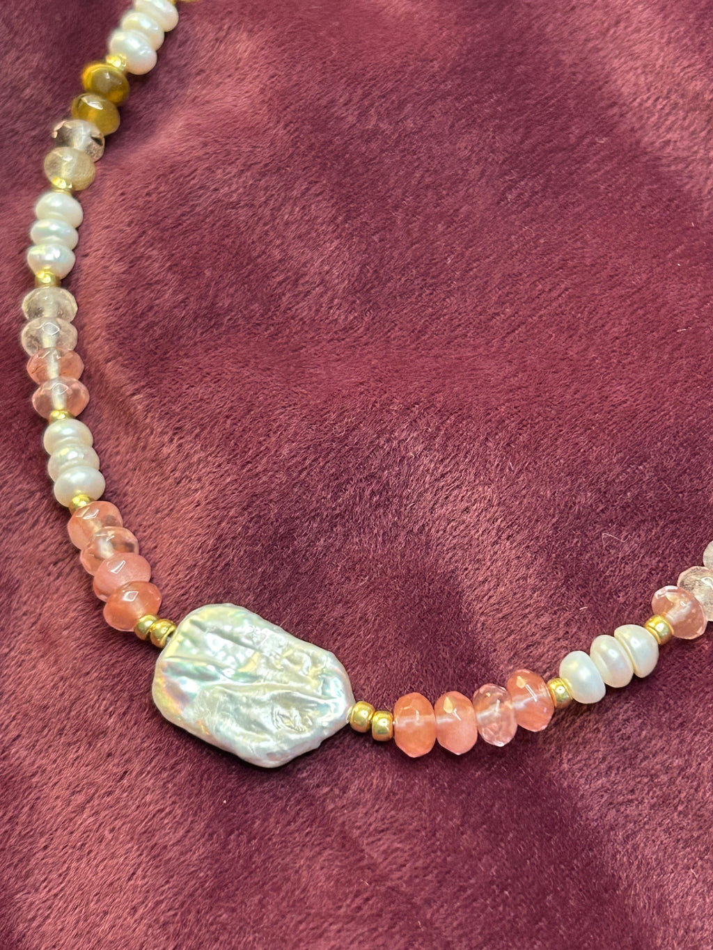 Necklace with pearls and pink stones on a purple fabric background