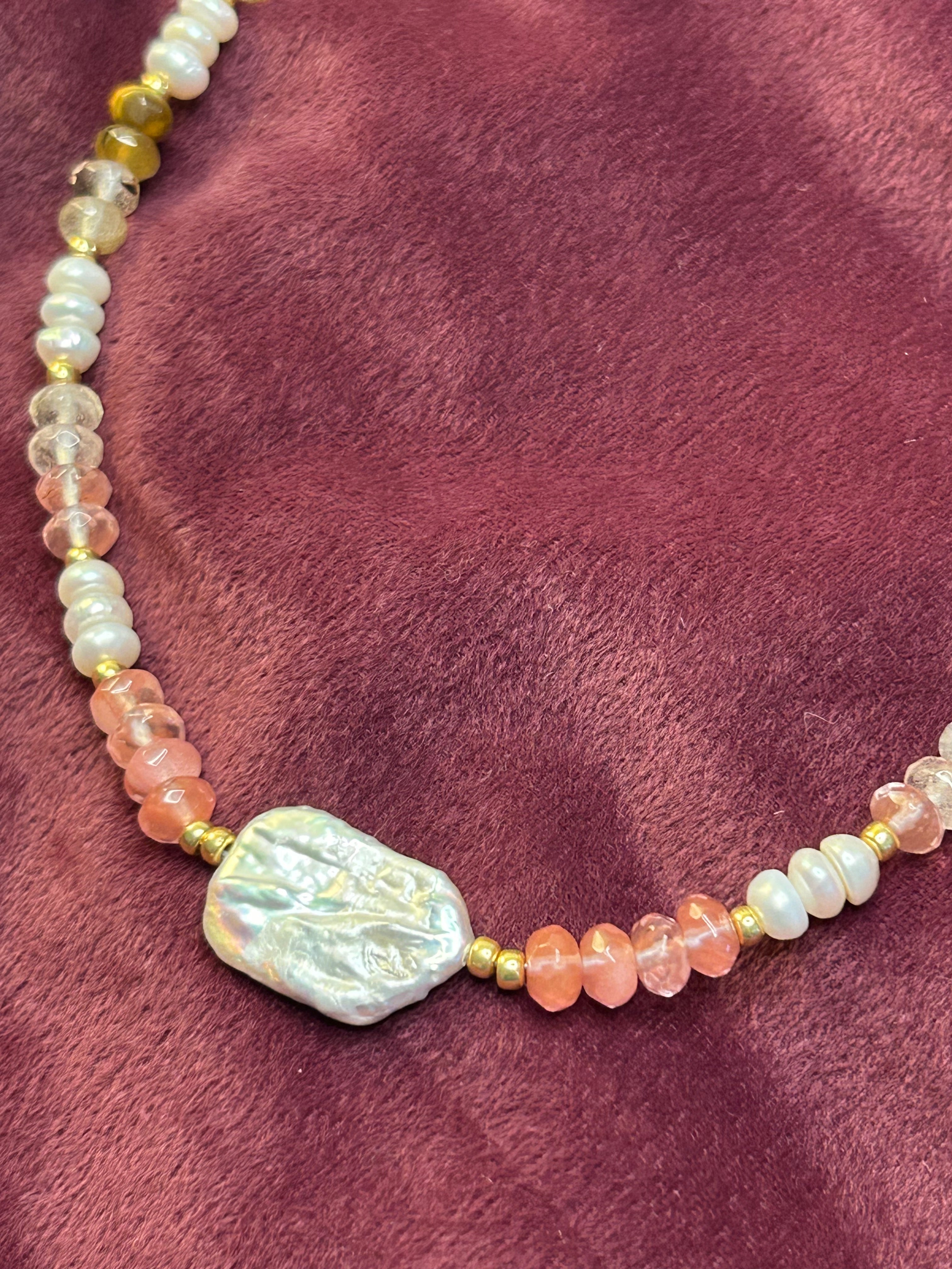 Necklace with pearls and pink stones on a purple fabric background