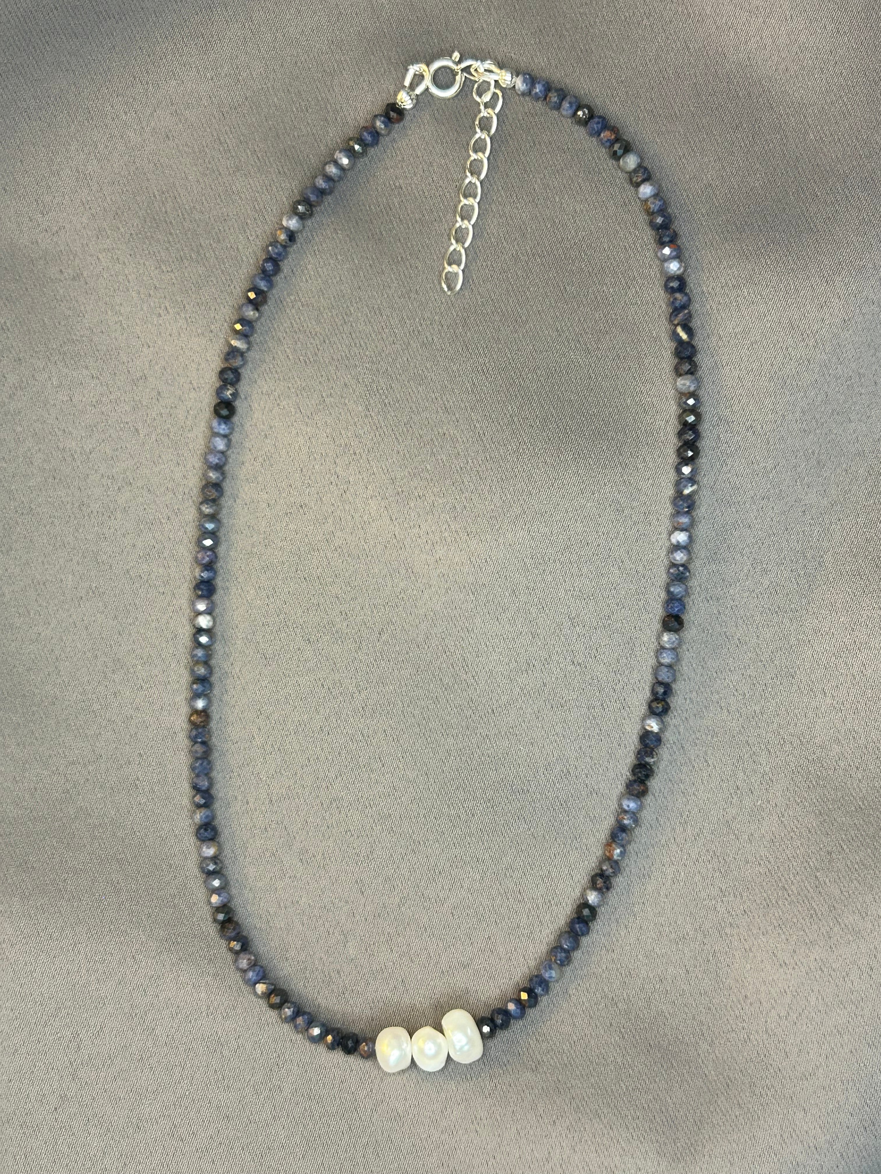 Necklace with blue beads and a silver clasp on a gray background