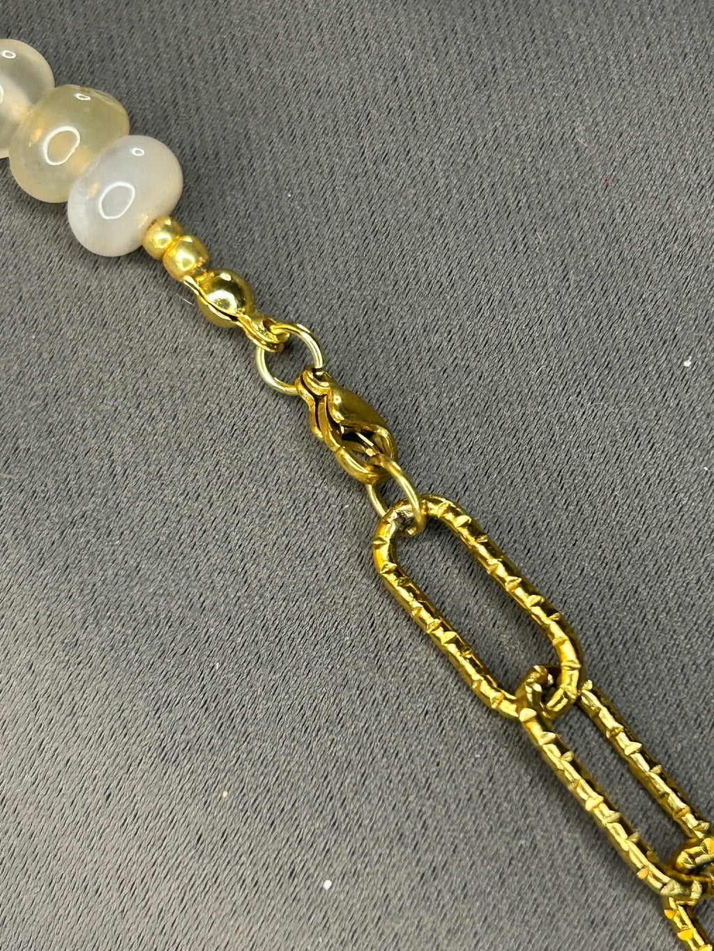 Gold chain with white beads on a gray background