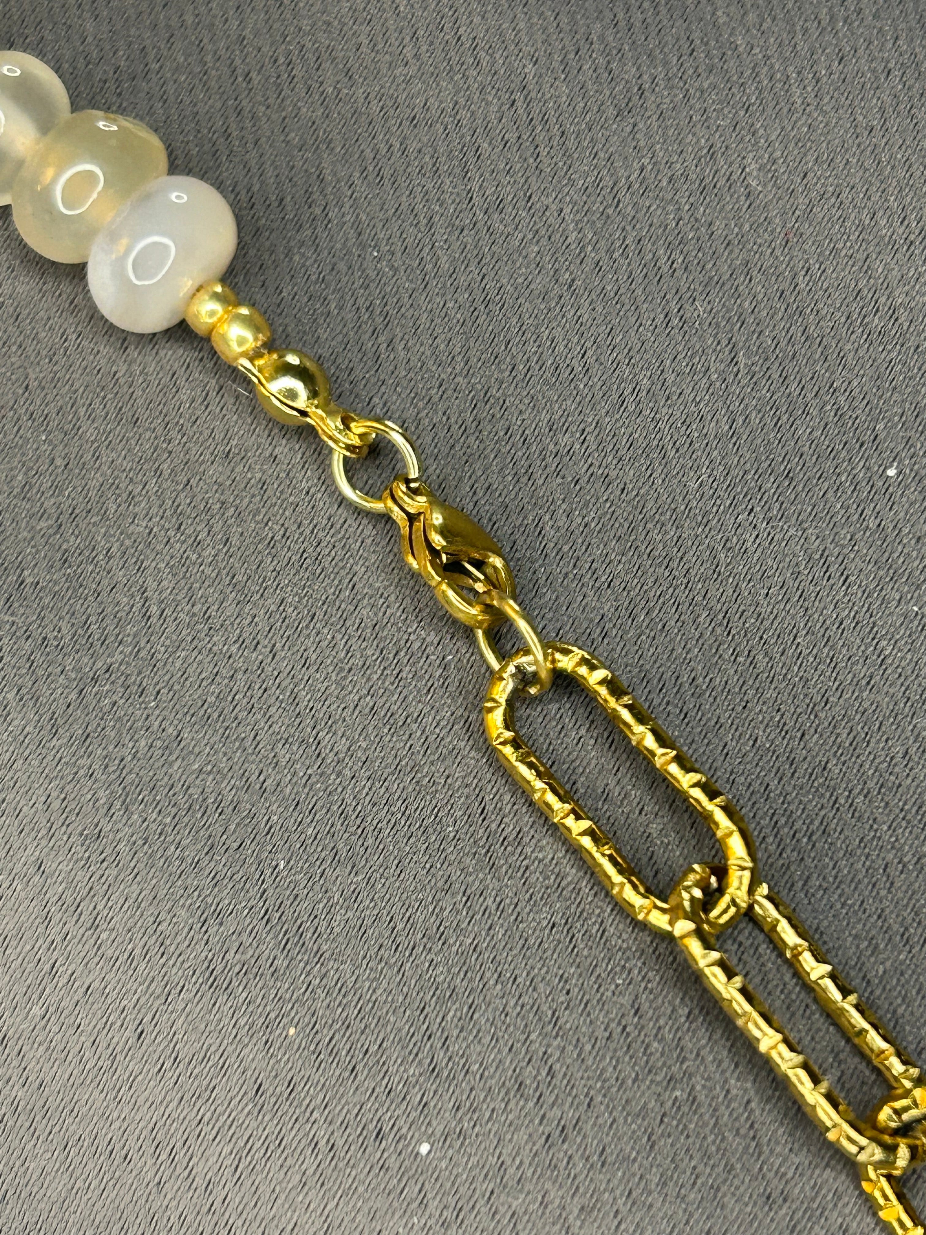 Gold chain with white beads on a gray background