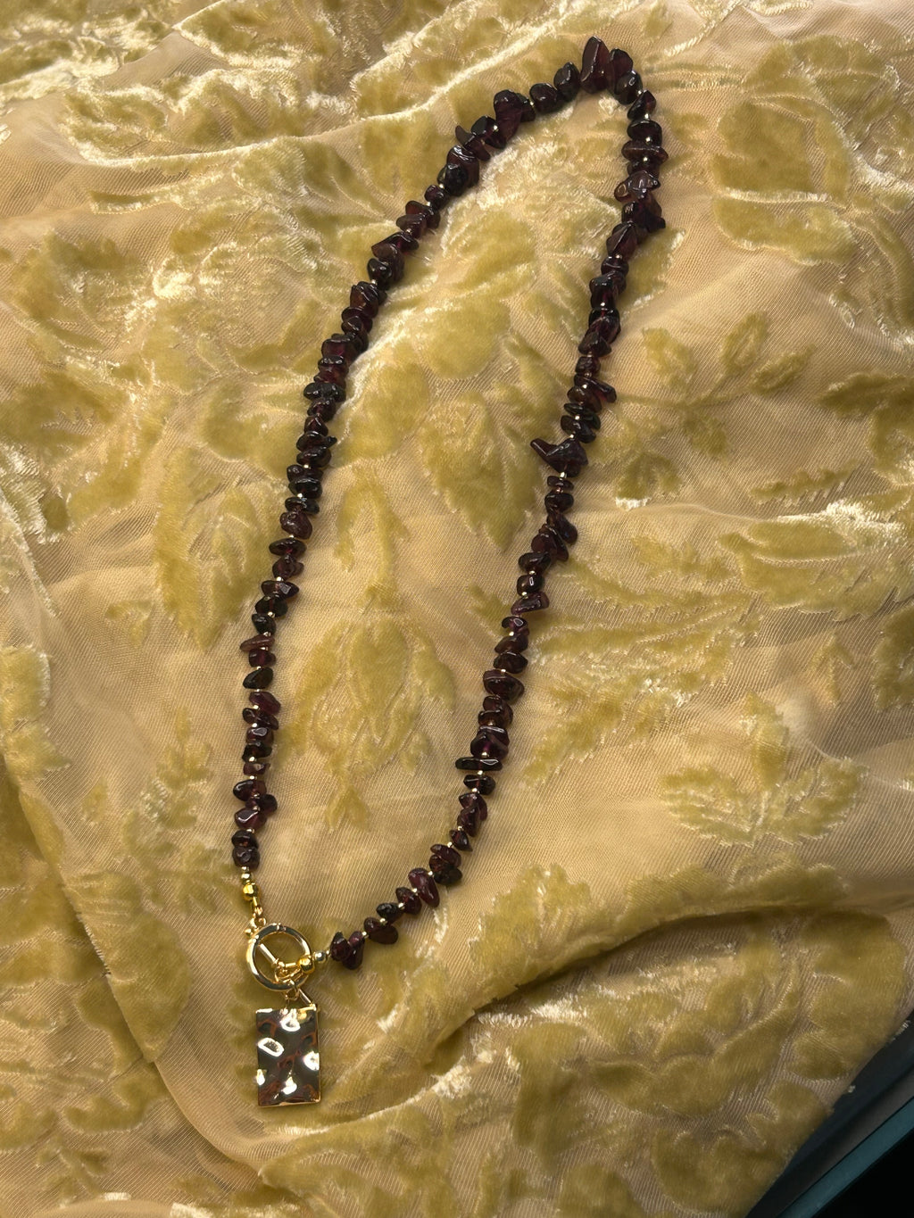 Necklace with dark beads on a textured beige fabric background