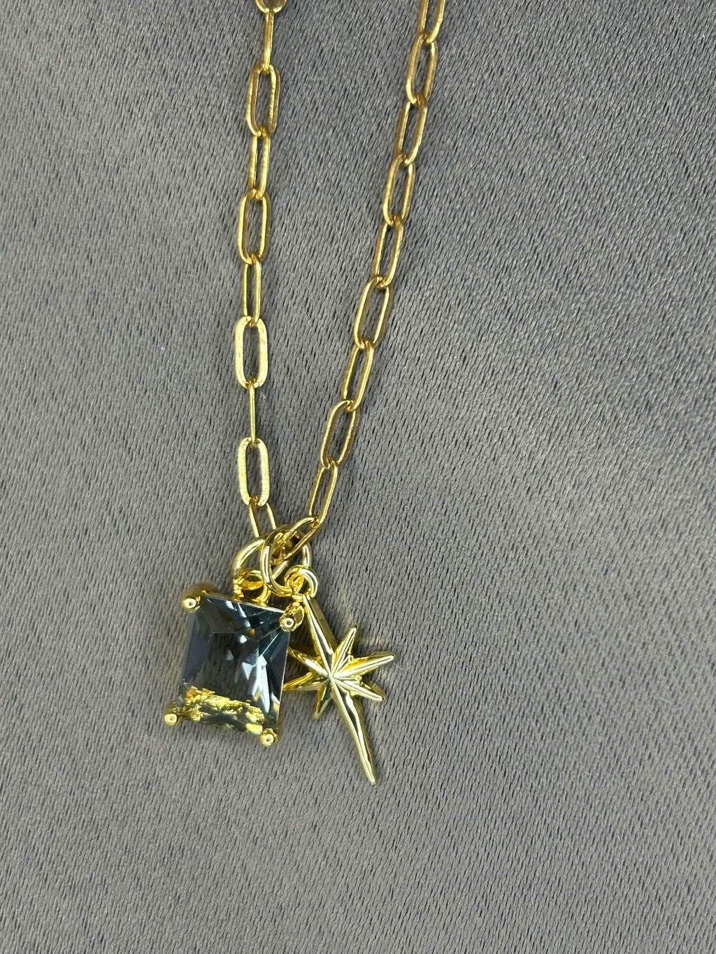 Gold necklace with a star-shaped pendant on a gray background