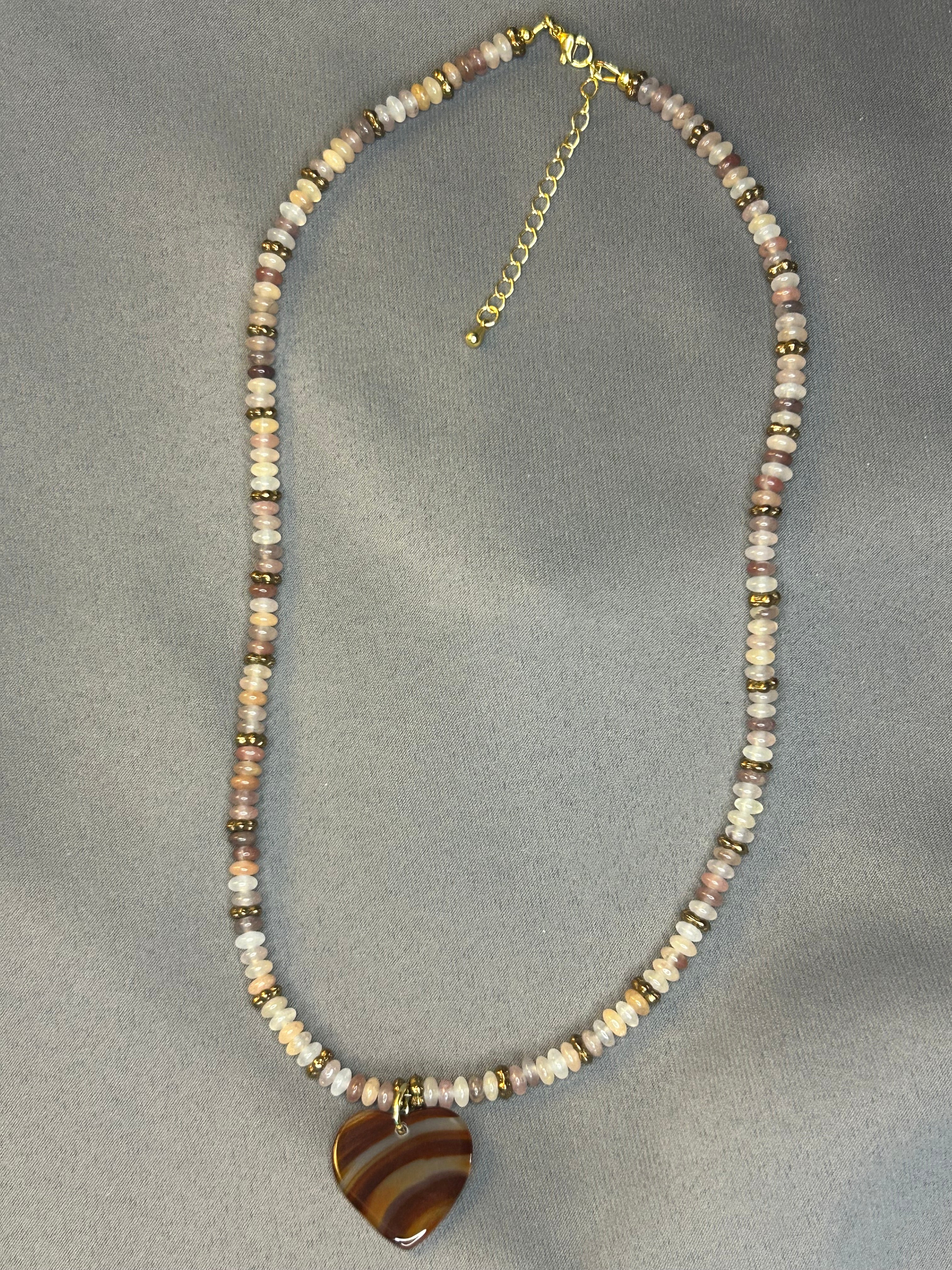 Necklace with beaded chain and large heart  pendant on a gray fabric background