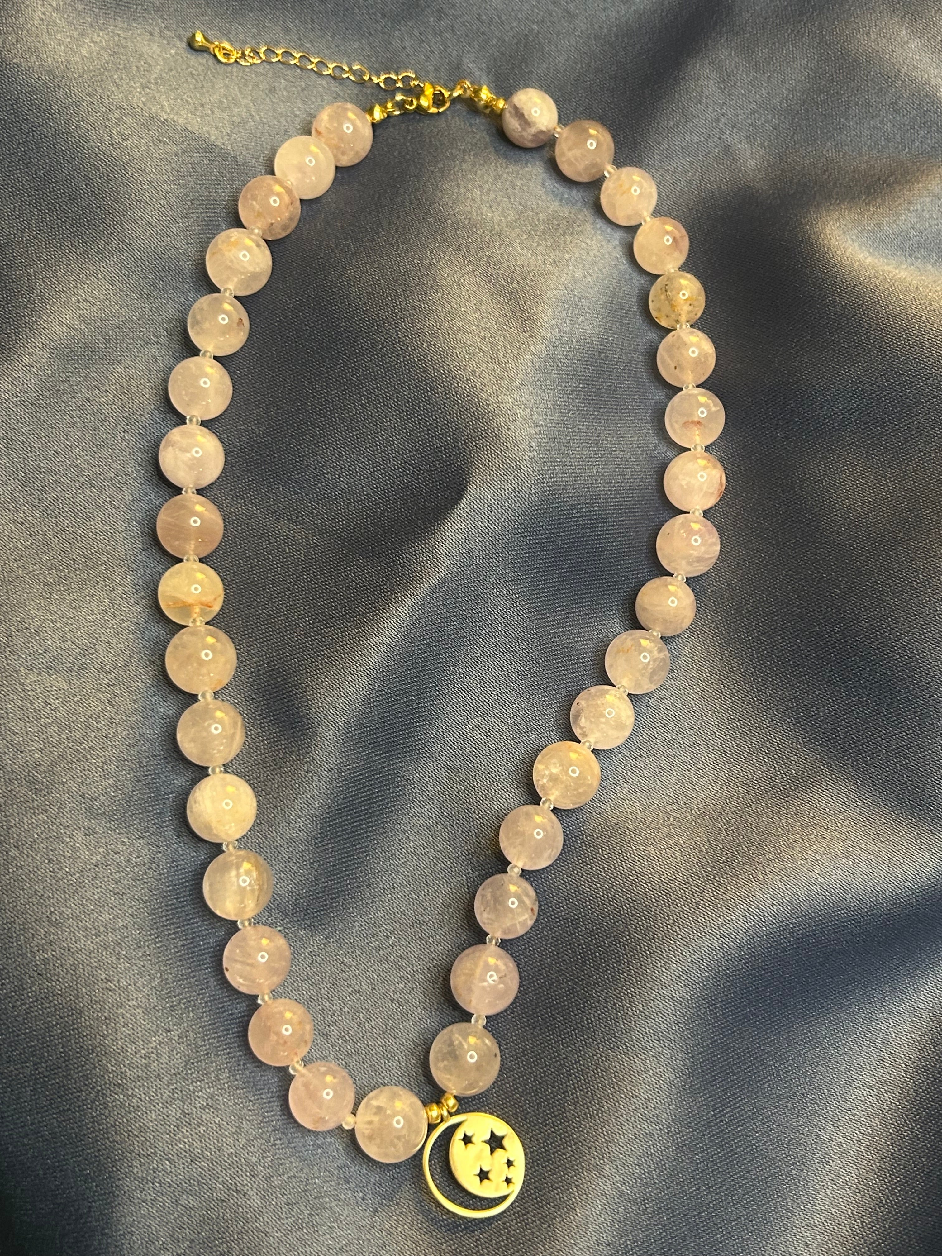 Necklace with pu7 beads and a gold charm on a gray fabric background