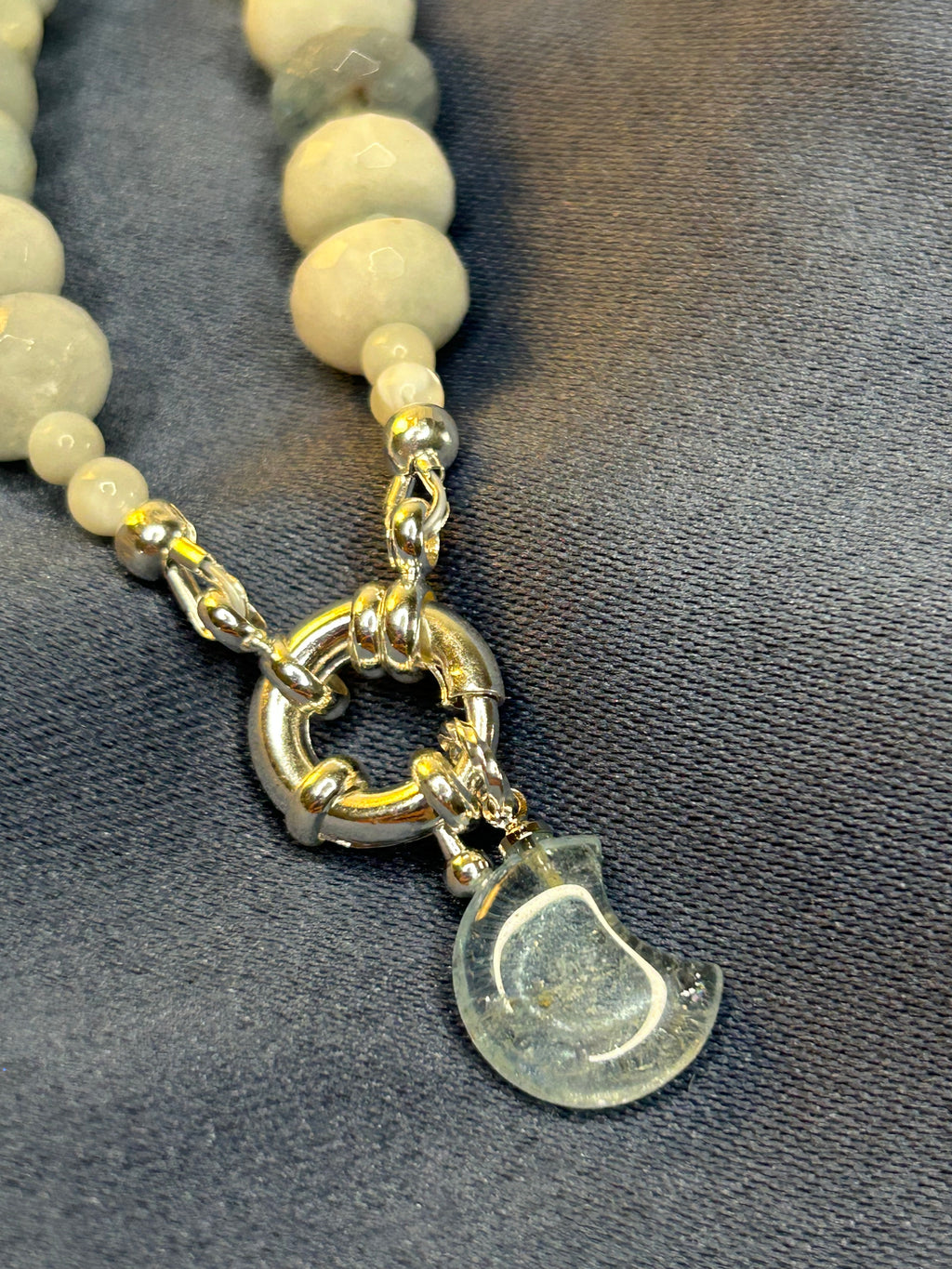Necklace with beige beads and a silver clasp on a gray fabric background