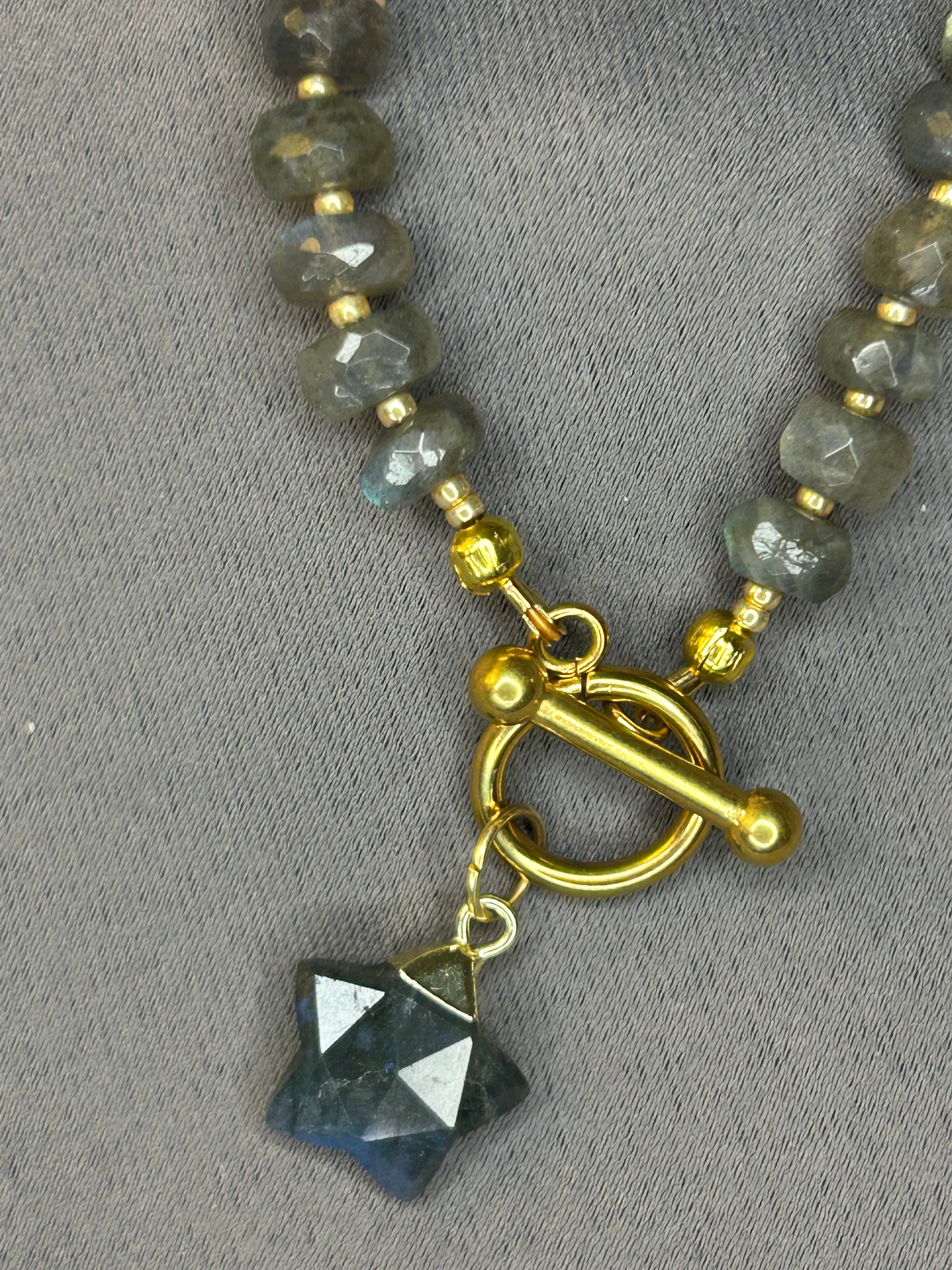 Necklace with gray beads and a gold clasp on a gray background