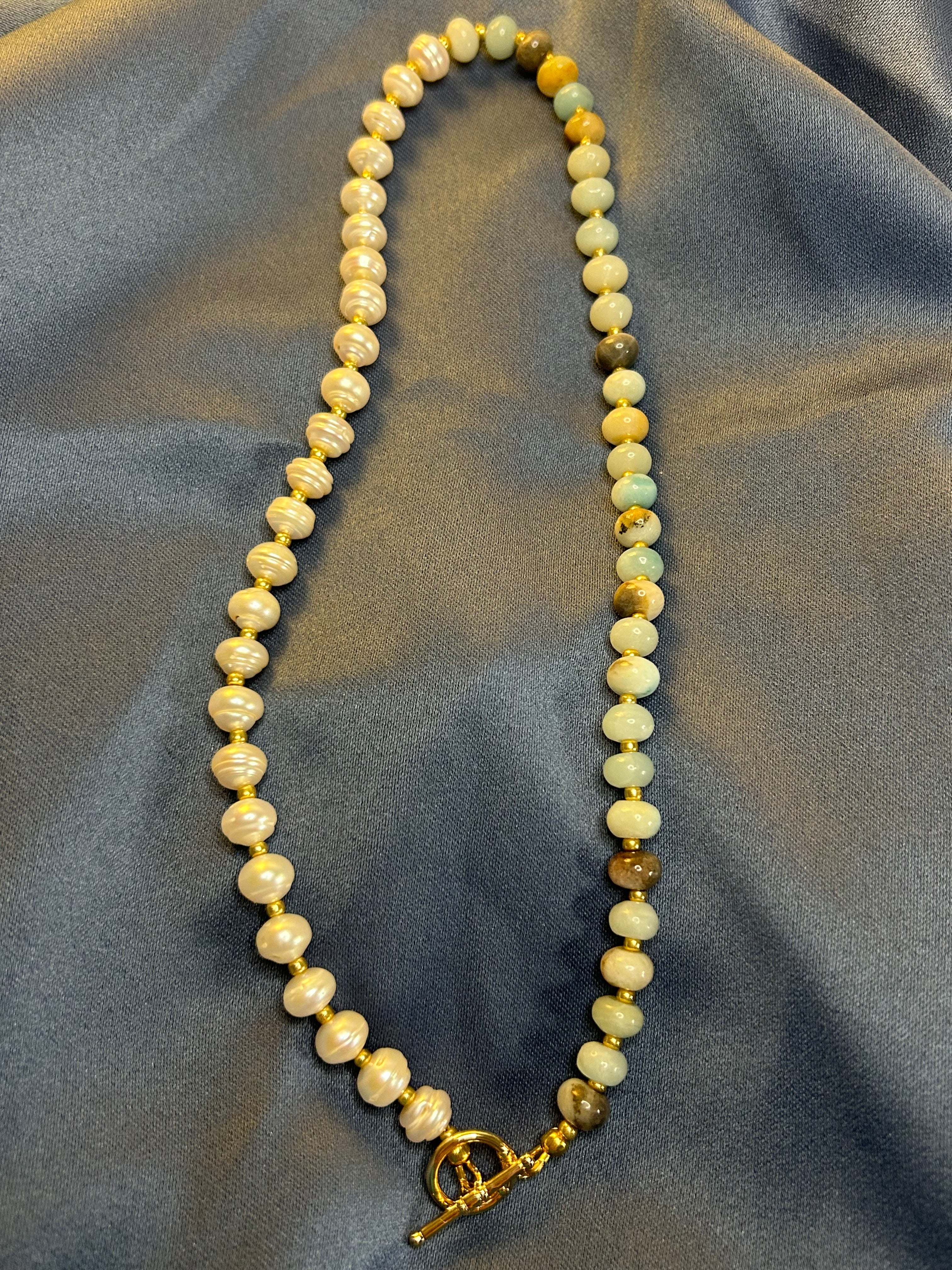Necklace with pearls and gemstones on a gray fabric background