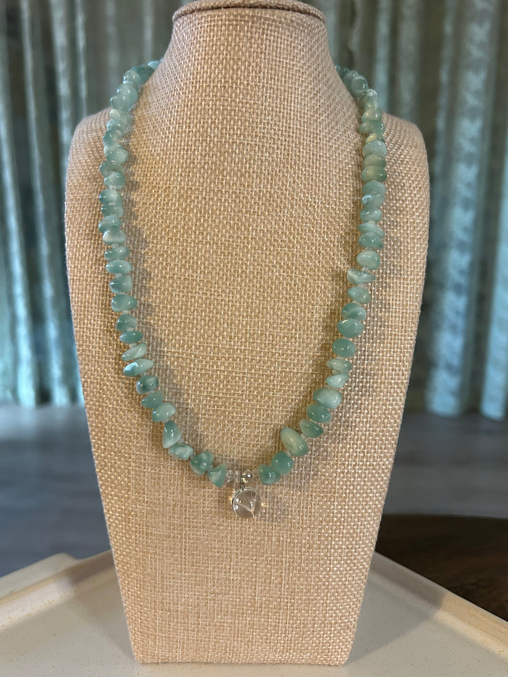 Turquoise beaded necklace on a beige jewelry display