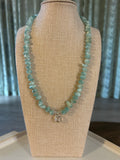 Turquoise beaded necklace on a beige jewelry display