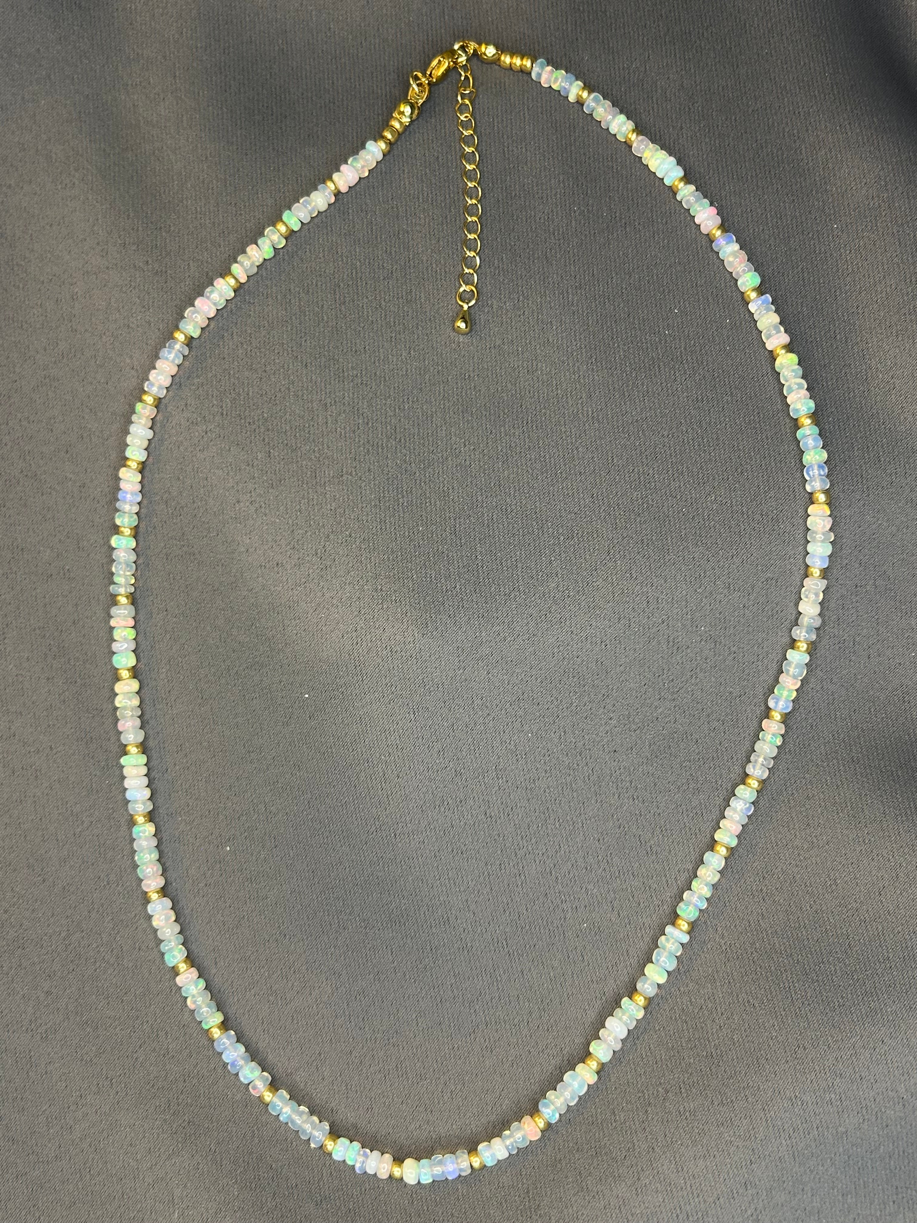 Small rondelle beaded necklace with gold accents on a gray background.