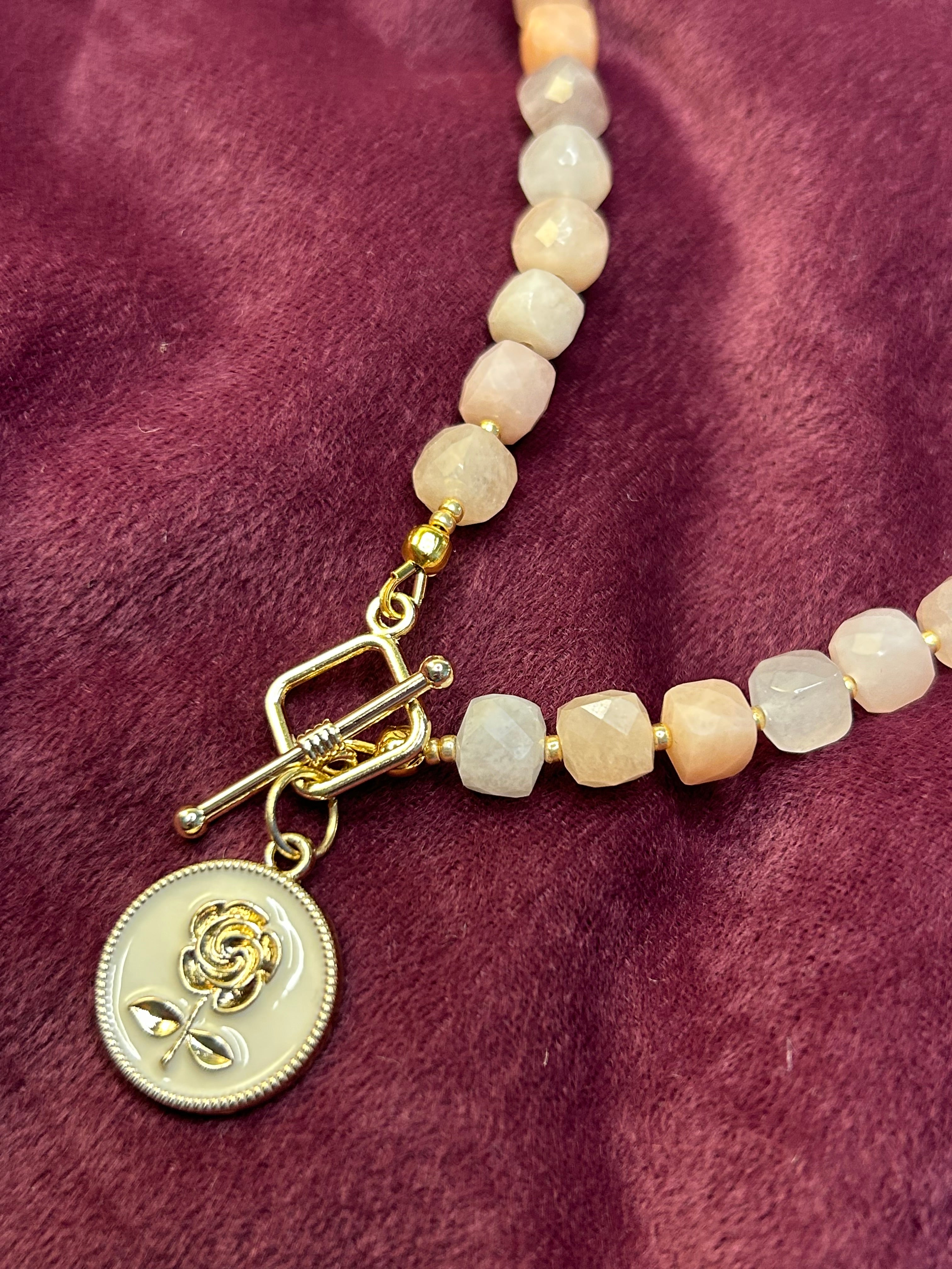 Necklace with beaded chain and gold clasp on a purple fabric background