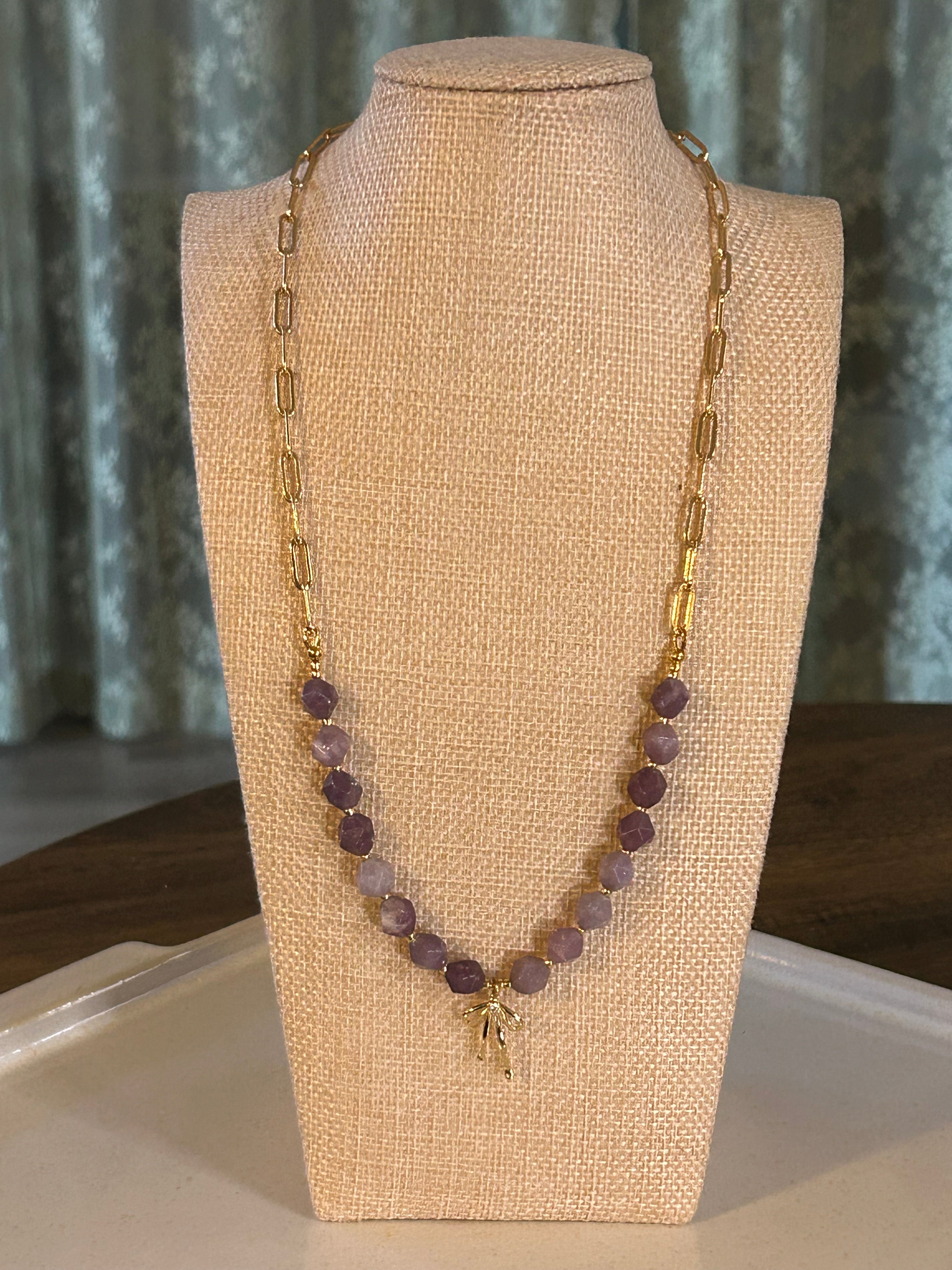 Purple beaded necklace on a mannequin bust with a neutral background