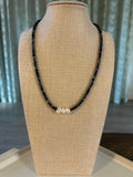 Blue beaded necklace with a pearl on a beige mannequin bust.