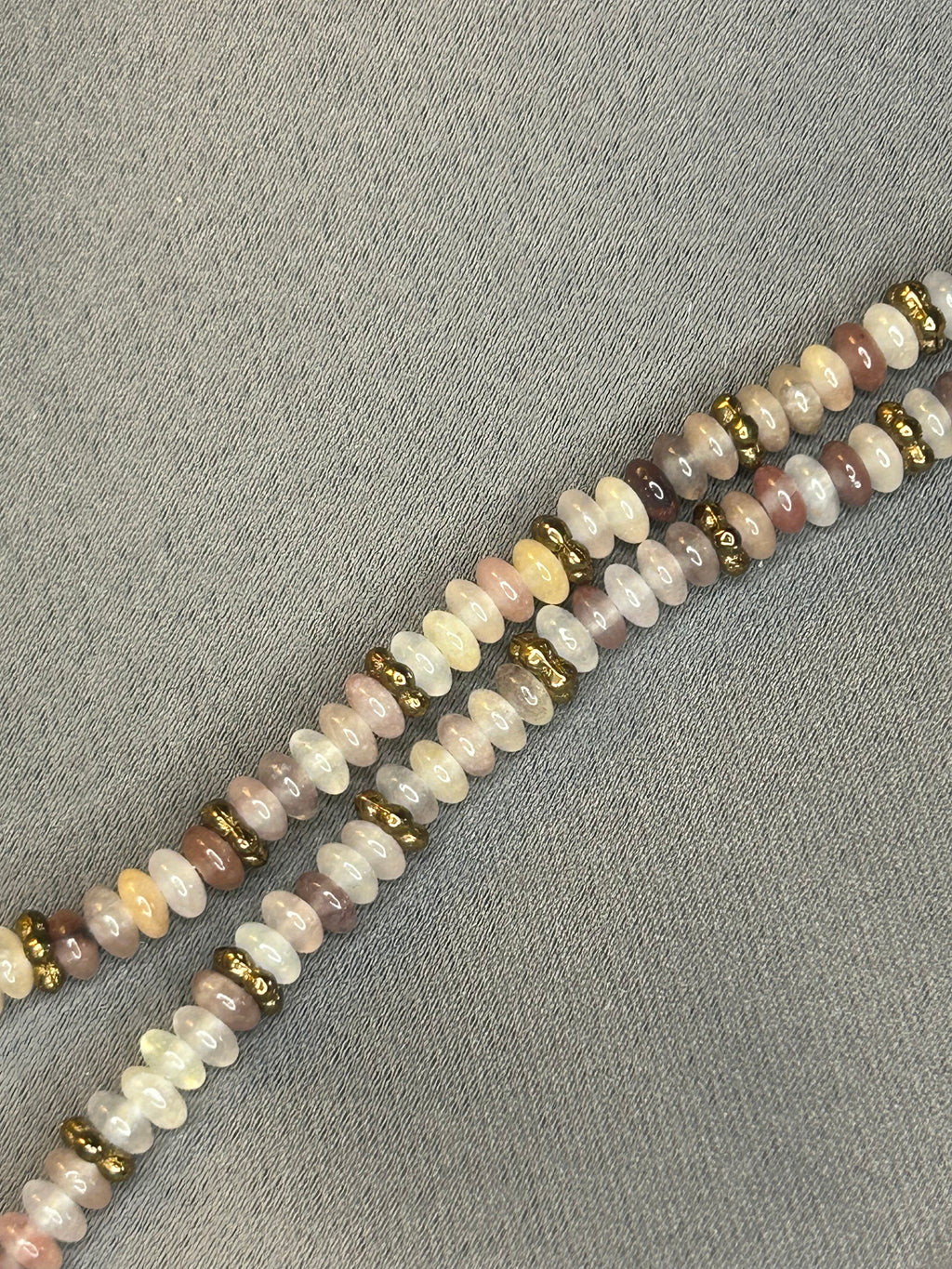Beaded necklace with multicolored beads on a gray fabric background