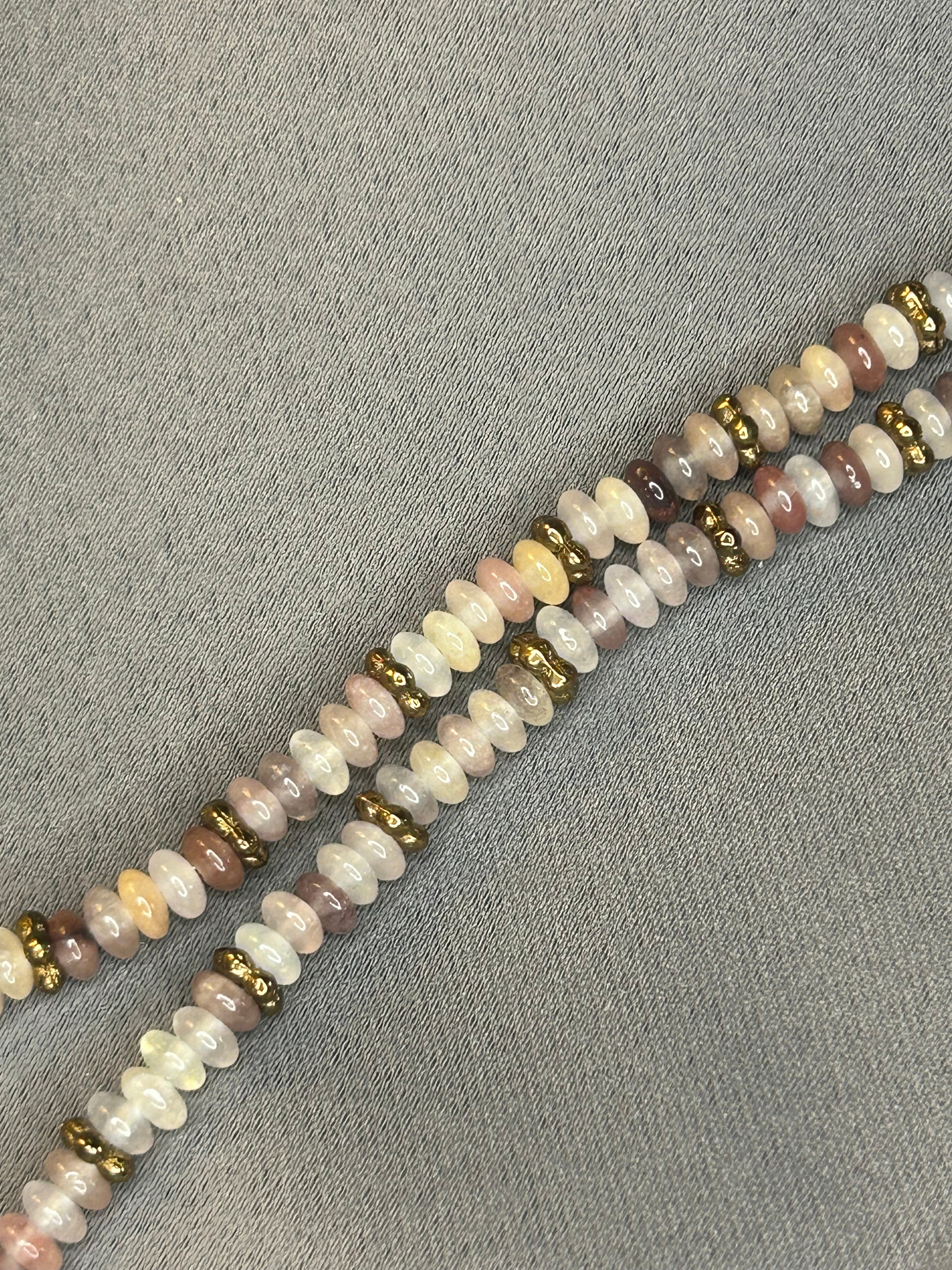 Beaded necklace with multicolored beads on a gray fabric background