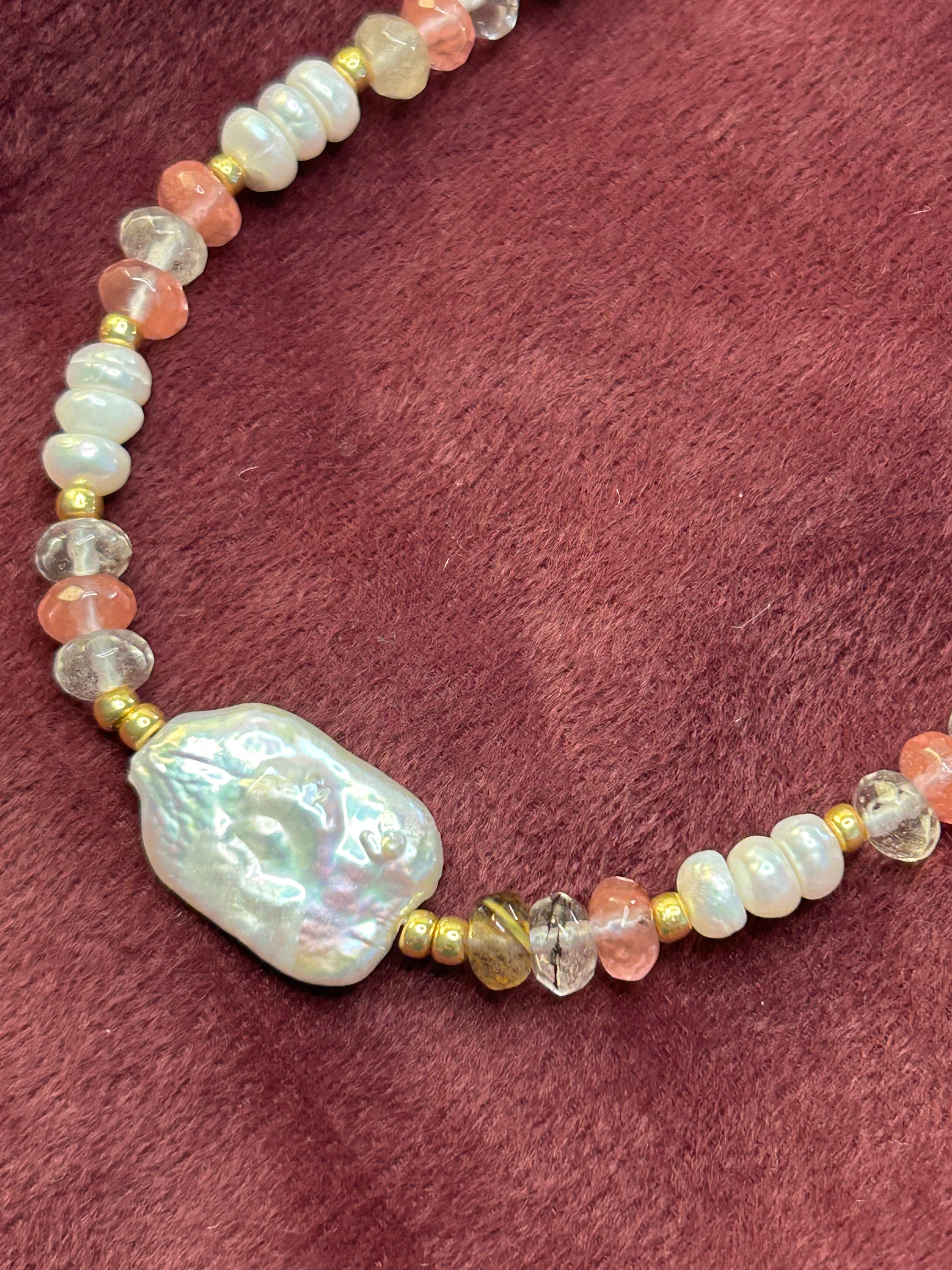 Necklace with large baroque pearl pendant on a maroon fabric background
