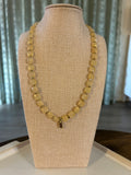 Gold necklace on a beige mannequin bust with a neutral background