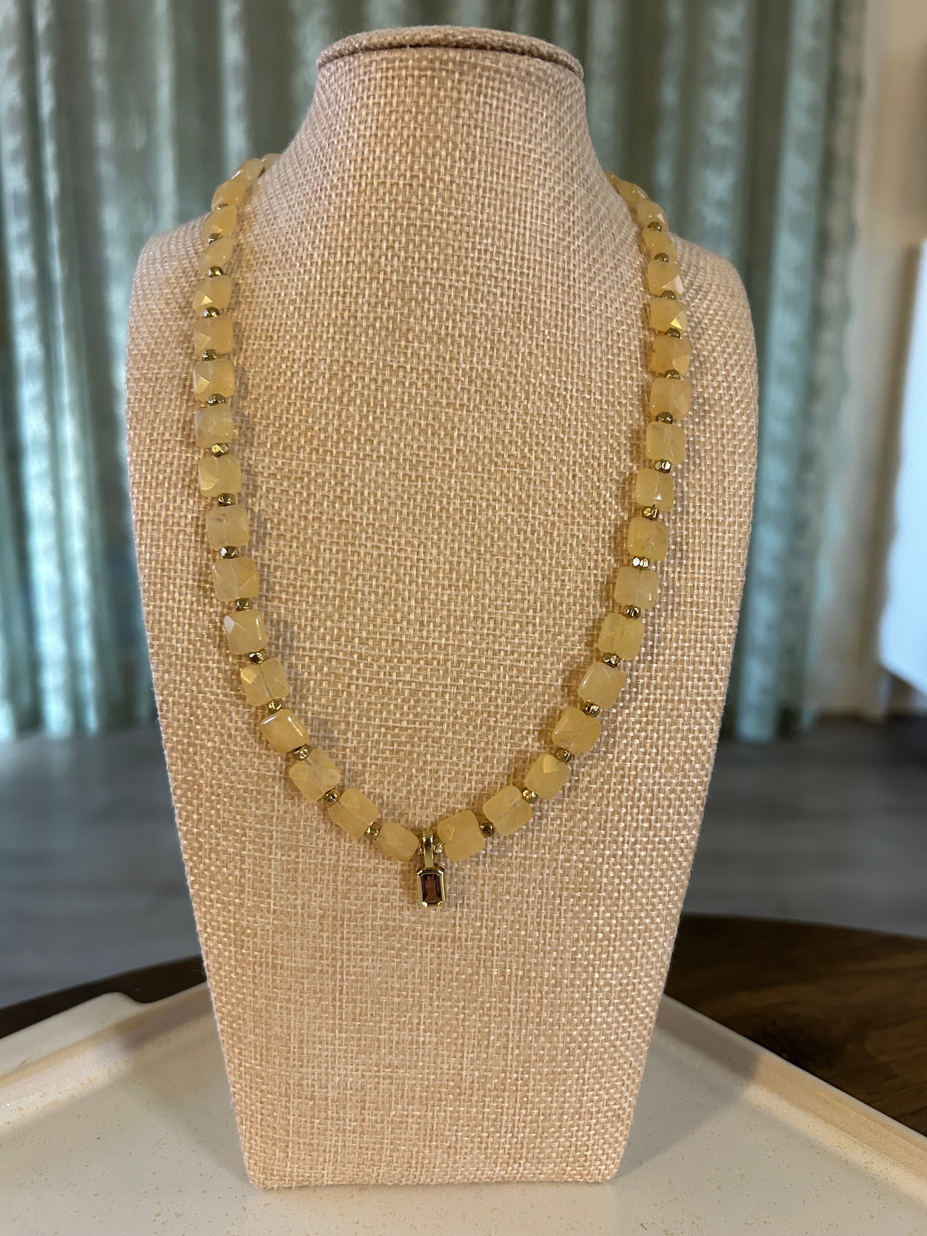 Gold necklace on a beige mannequin bust with a neutral background