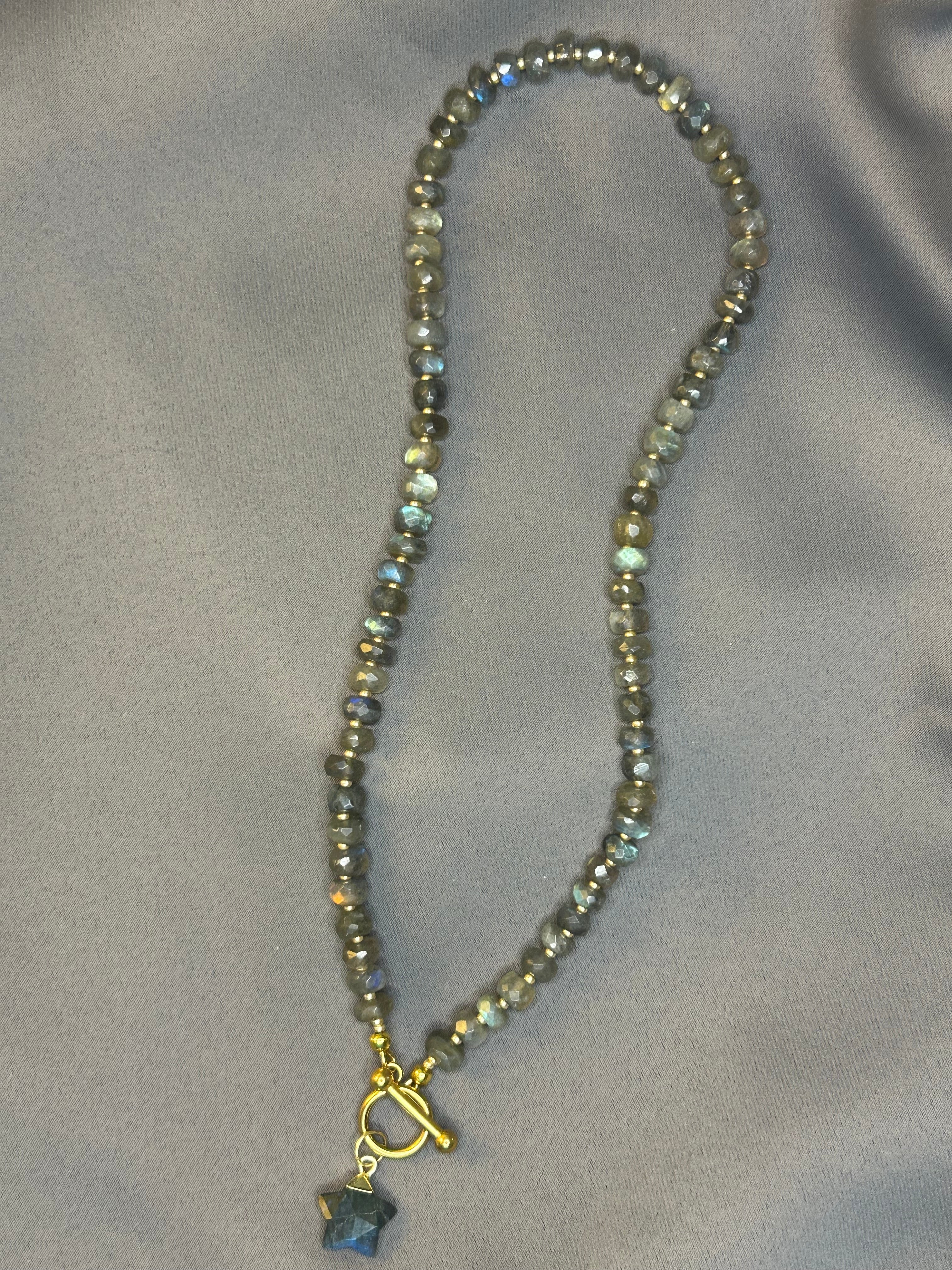 Beaded necklace with a star-shaped pendant on a gray fabric background