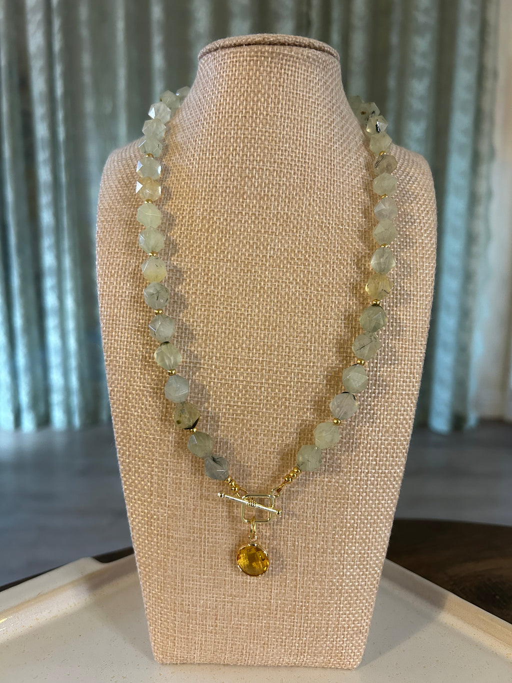 Necklace with green beads on a beige display stand