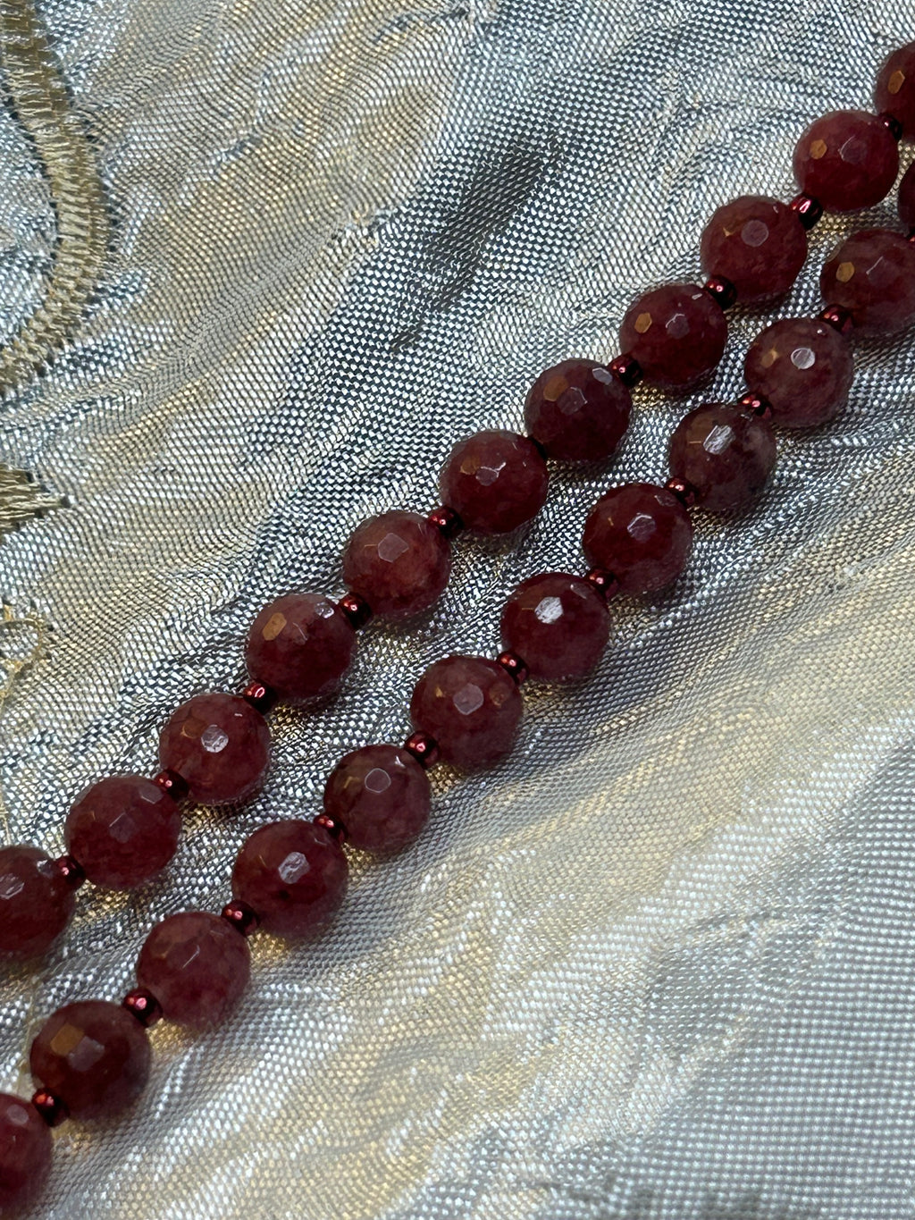 Necklace with dark red beads on a textured fabric background