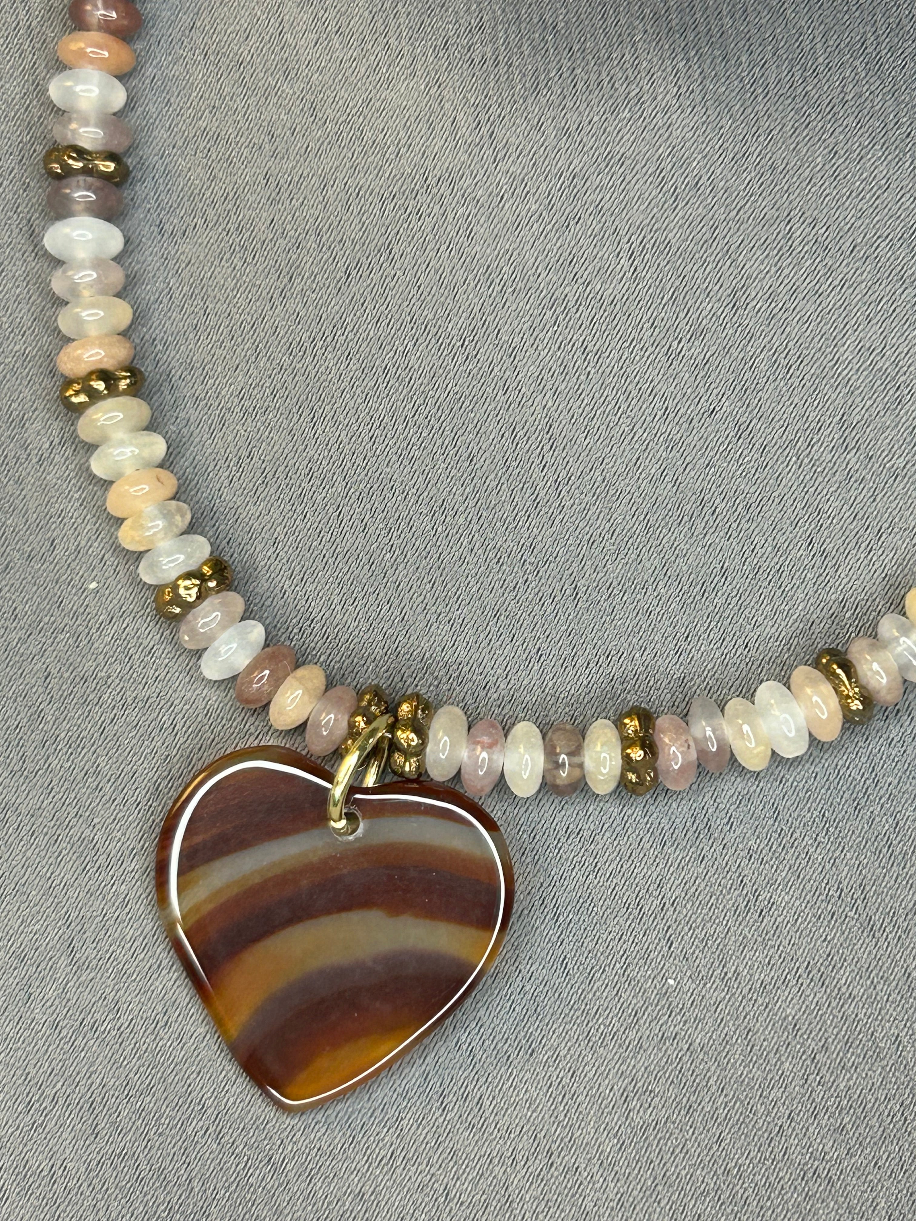 Necklace with beaded chain and large stone pendant on a gray background
