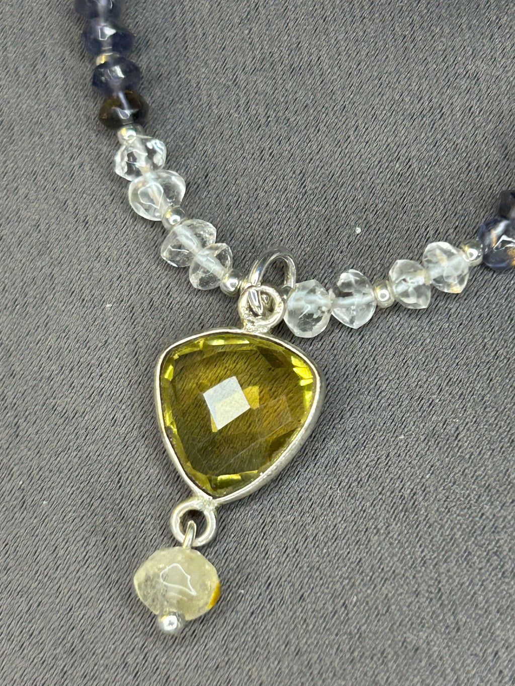 Necklace with yellow pendant and beaded chain on gray background