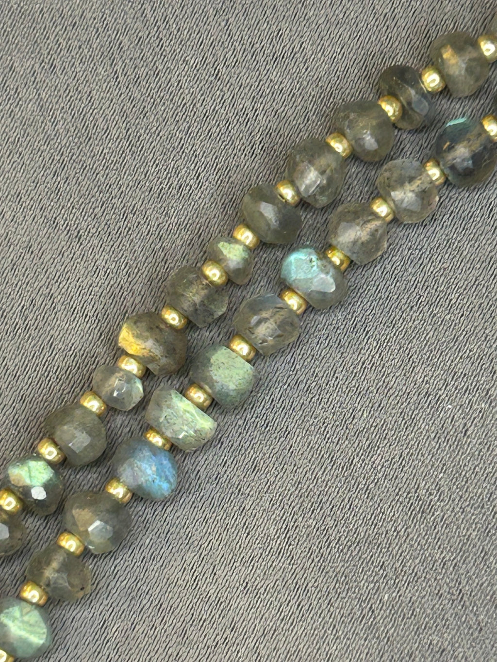String of gray beads with gold accents on a textured gray surface
