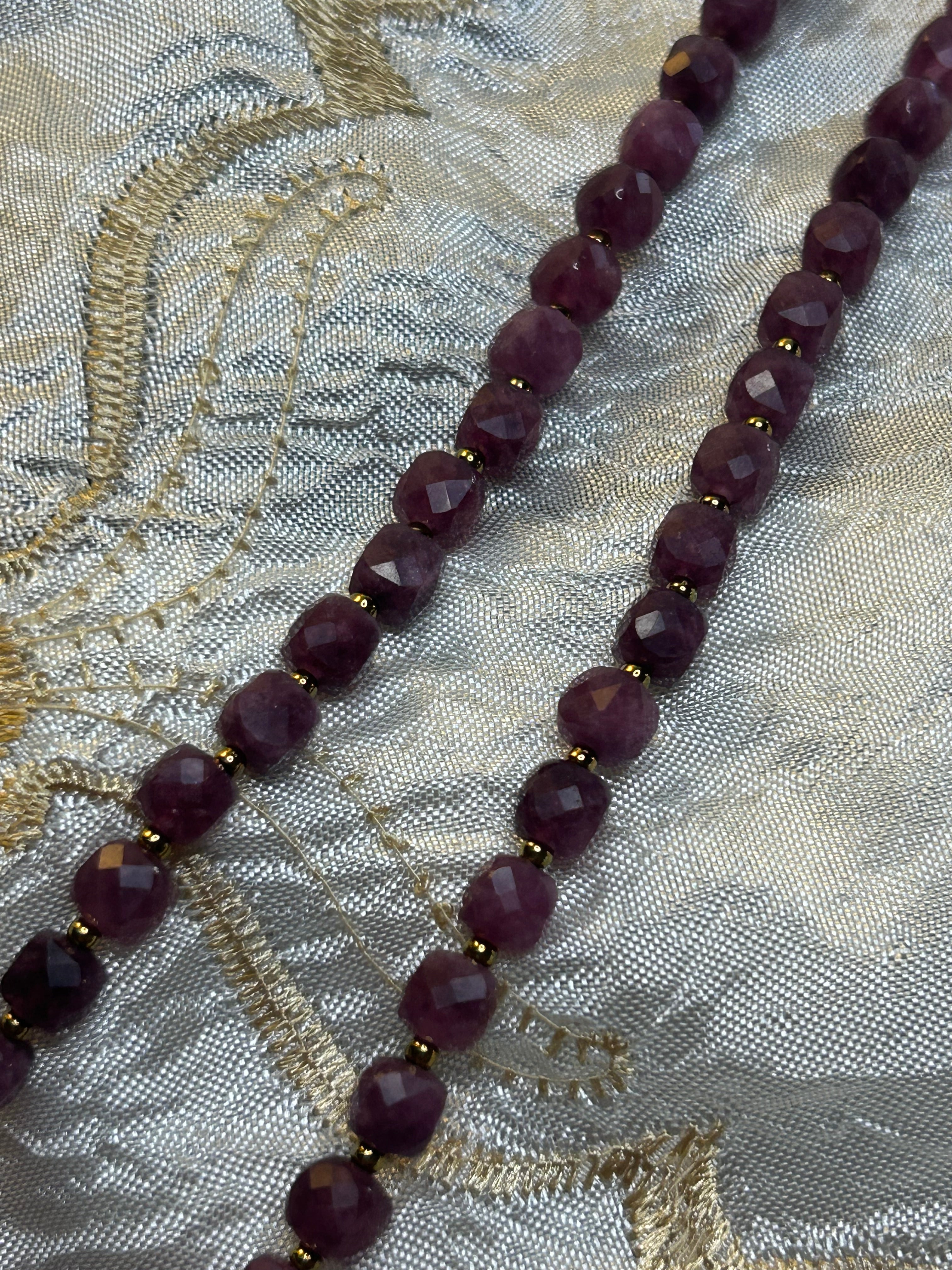 Necklace with dark beads on a textured fabric background