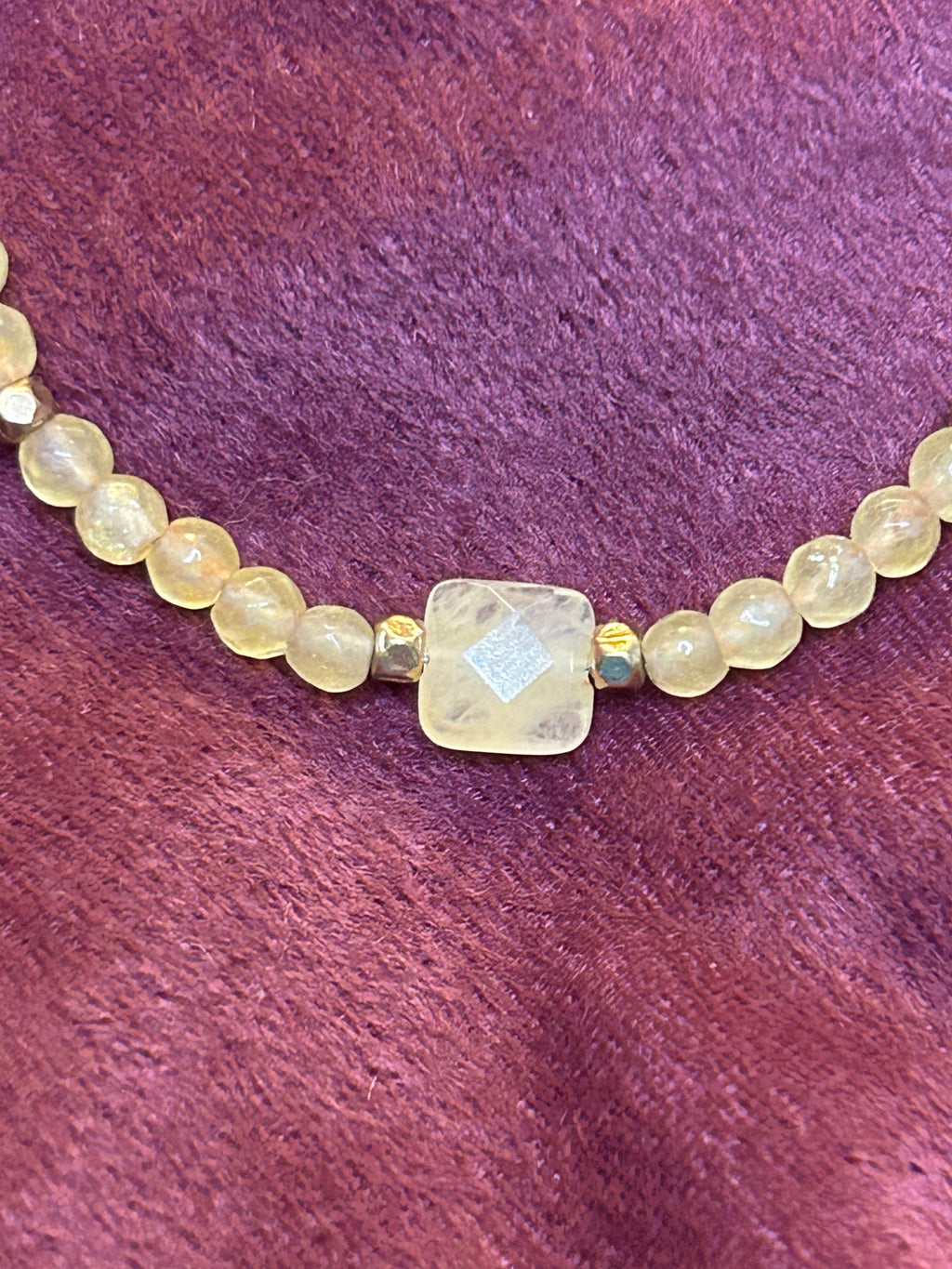 Beaded necklace with a large central stone on a purple textured background
