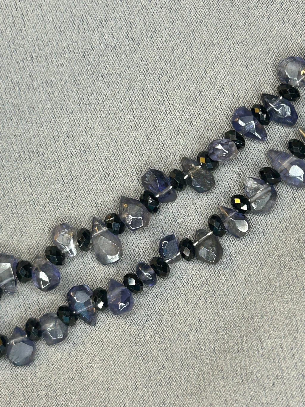 Necklace with faceted gemstones on a gray fabric background