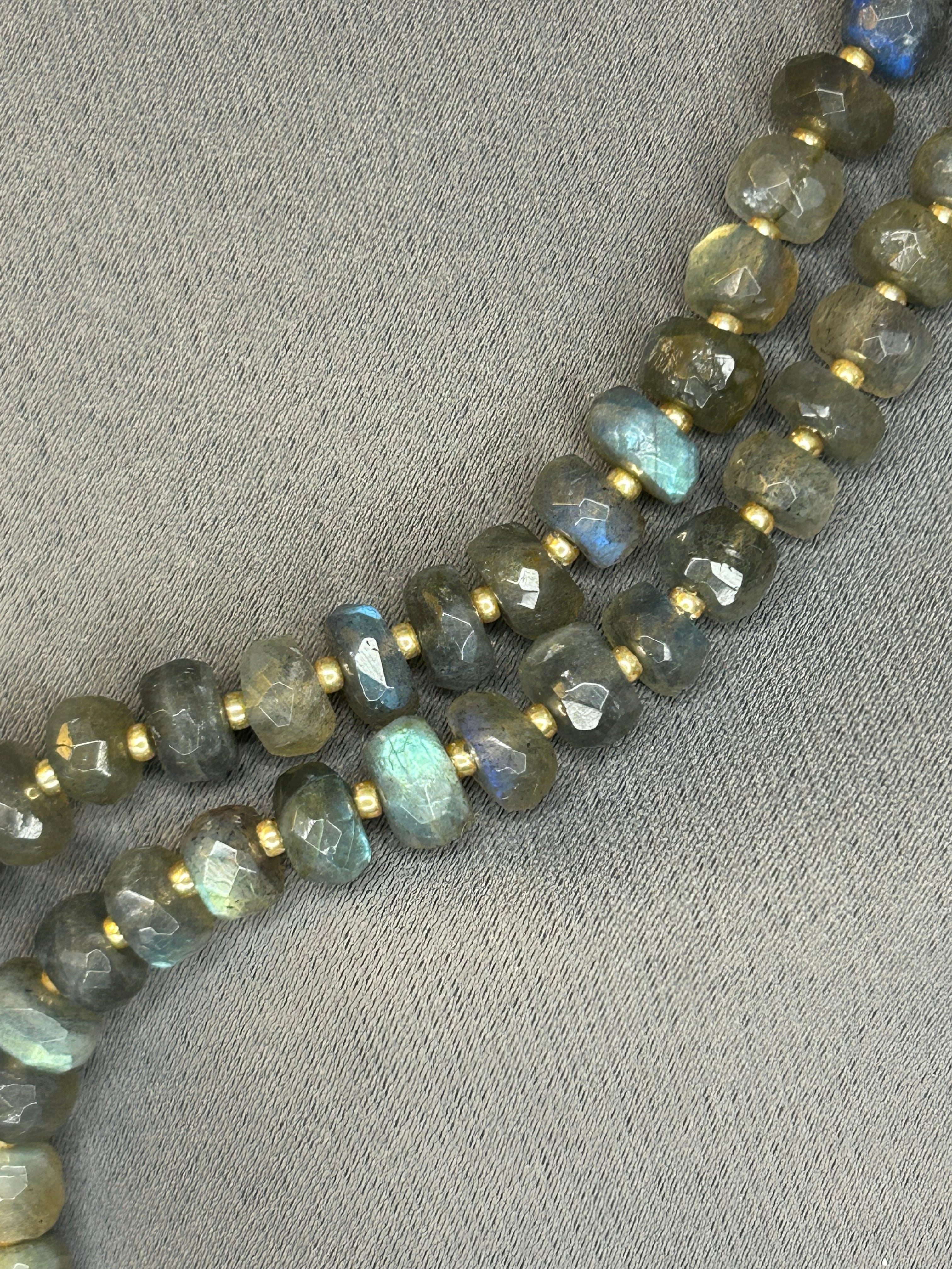String of faceted gemstones on a gray fabric background