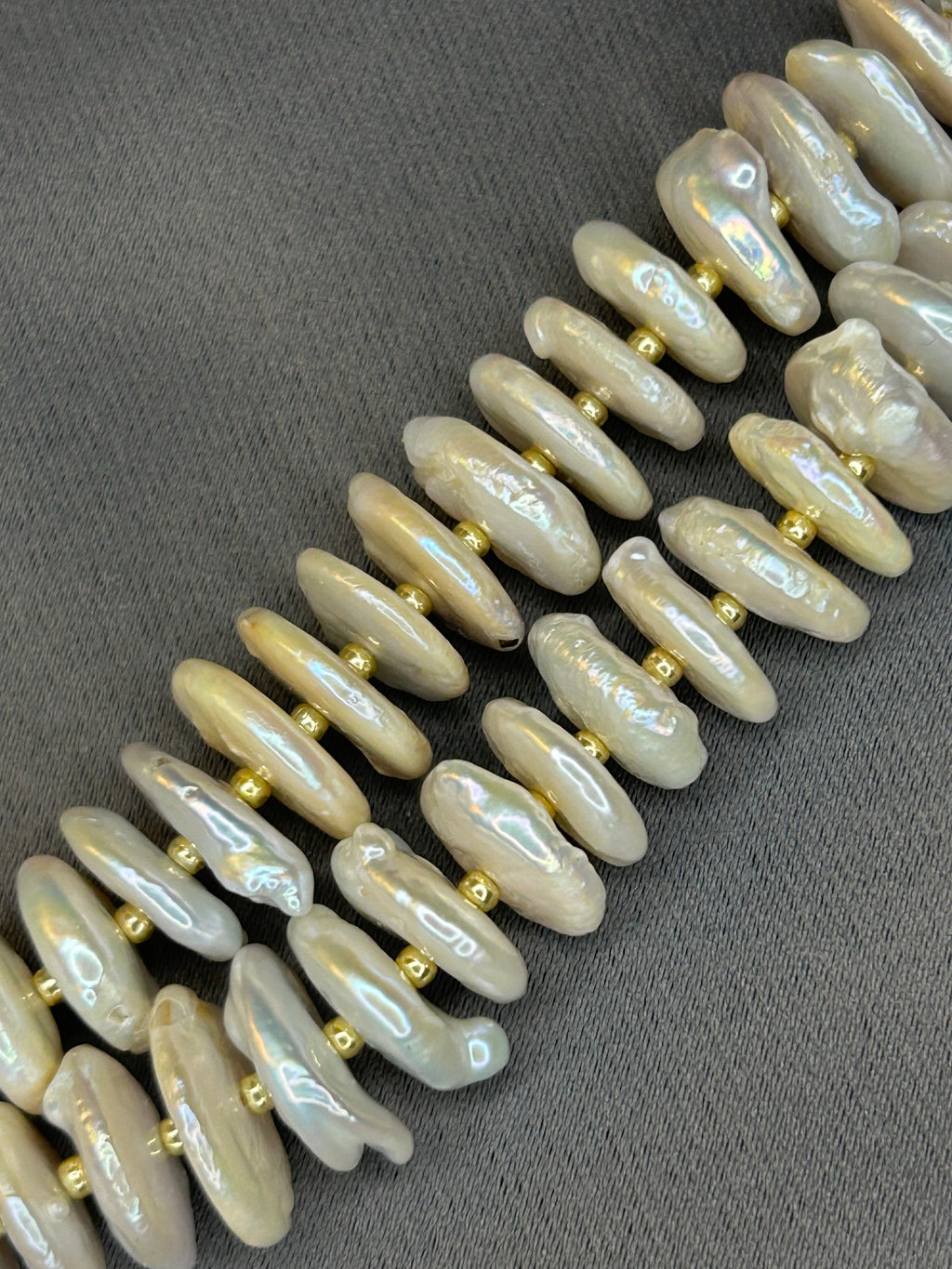 Row of pearl rondelle beads with gold accents on a dark gray background