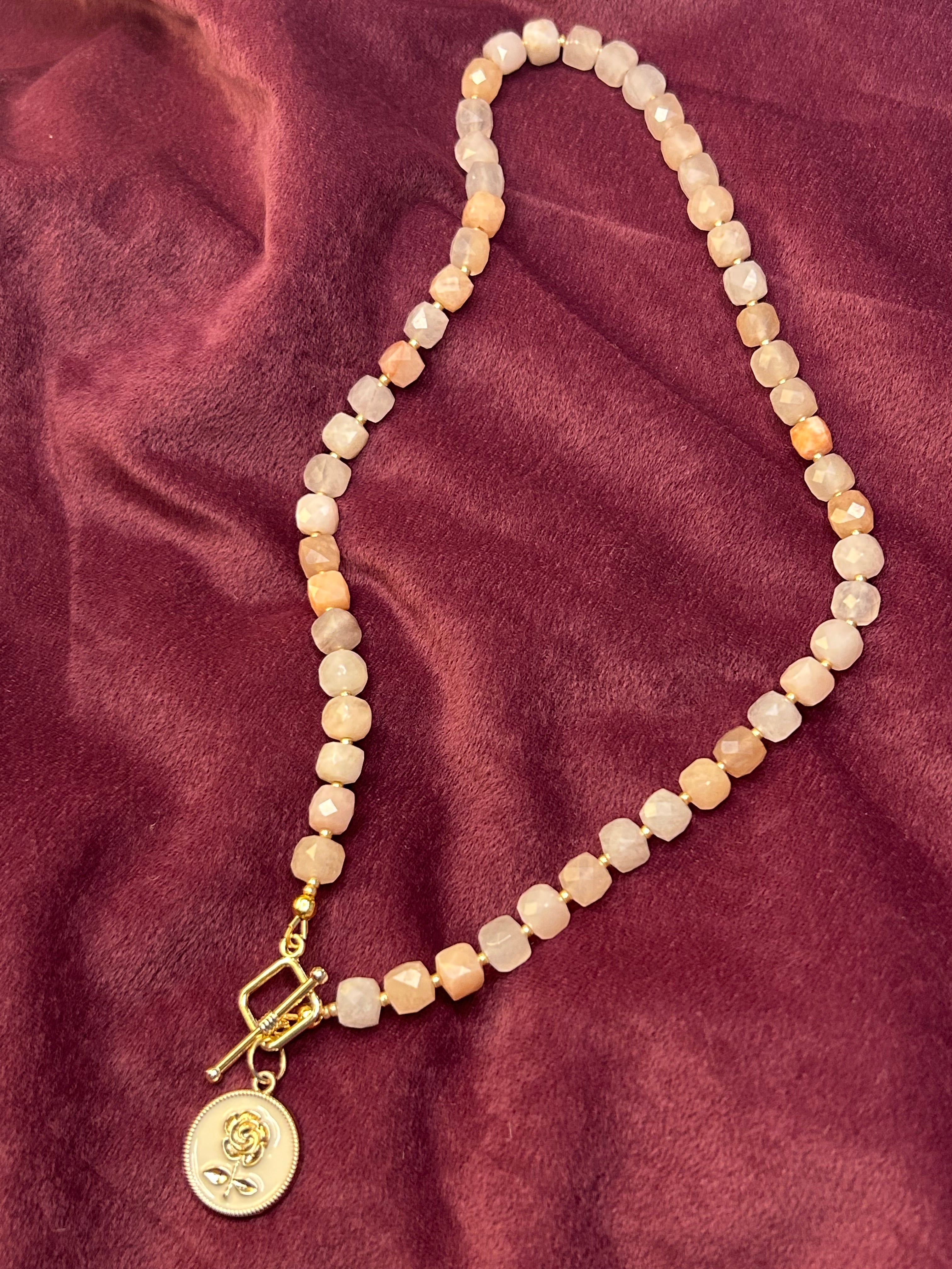 Necklace with beaded chain and gold clasp on a maroon fabric background