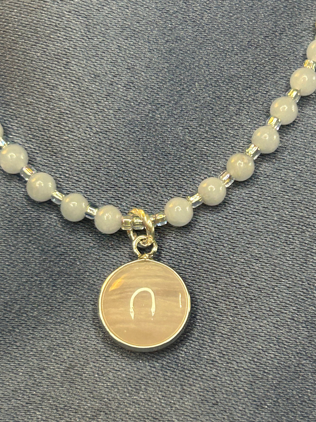 Beaded necklace with a round pendant on a gray fabric background