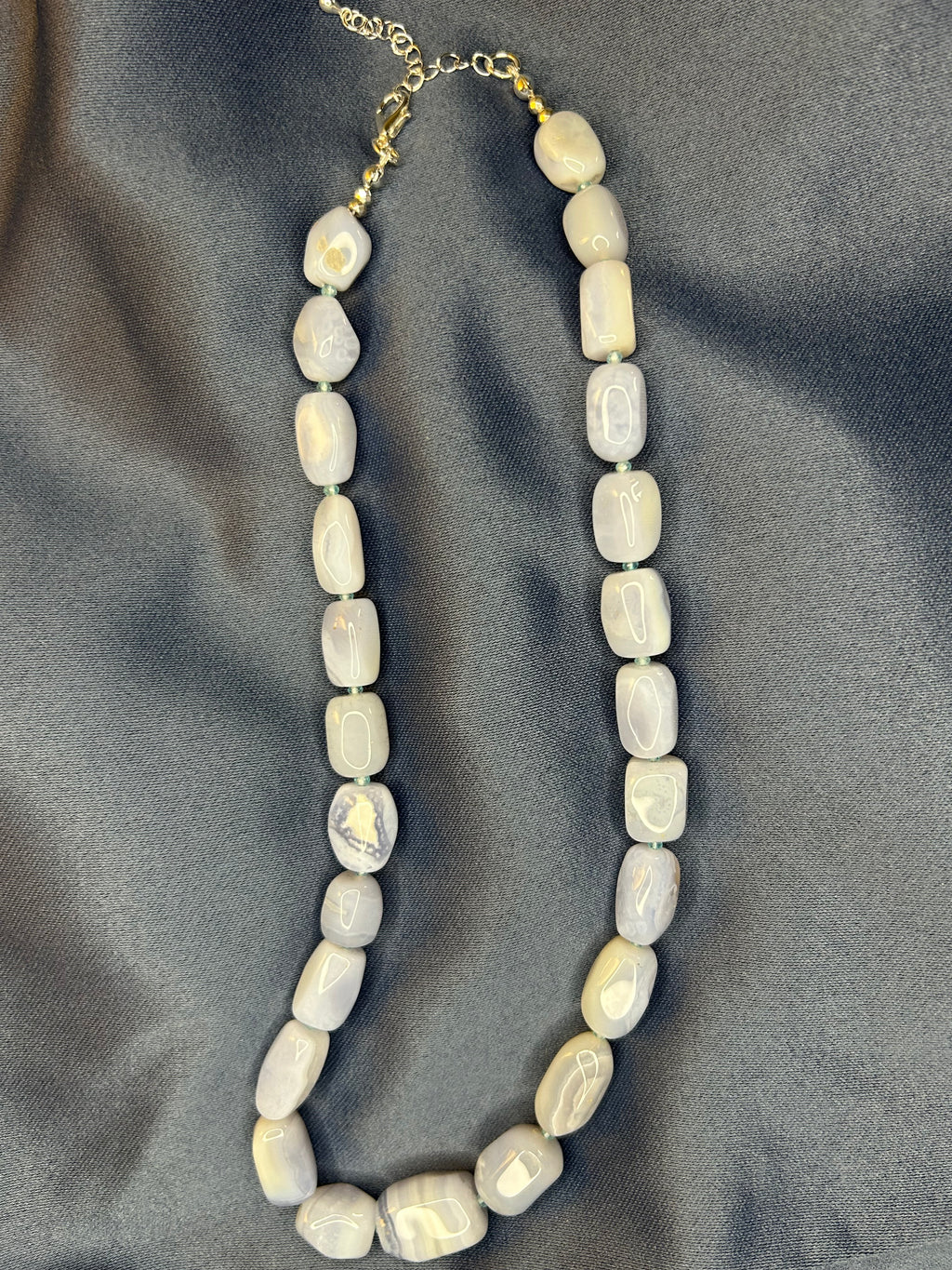 Necklace with blue beads on a gray fabric background