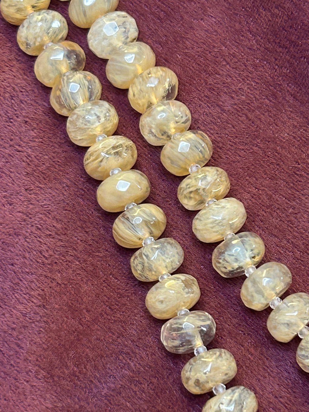 Necklace with light-colored beads on a maroon background