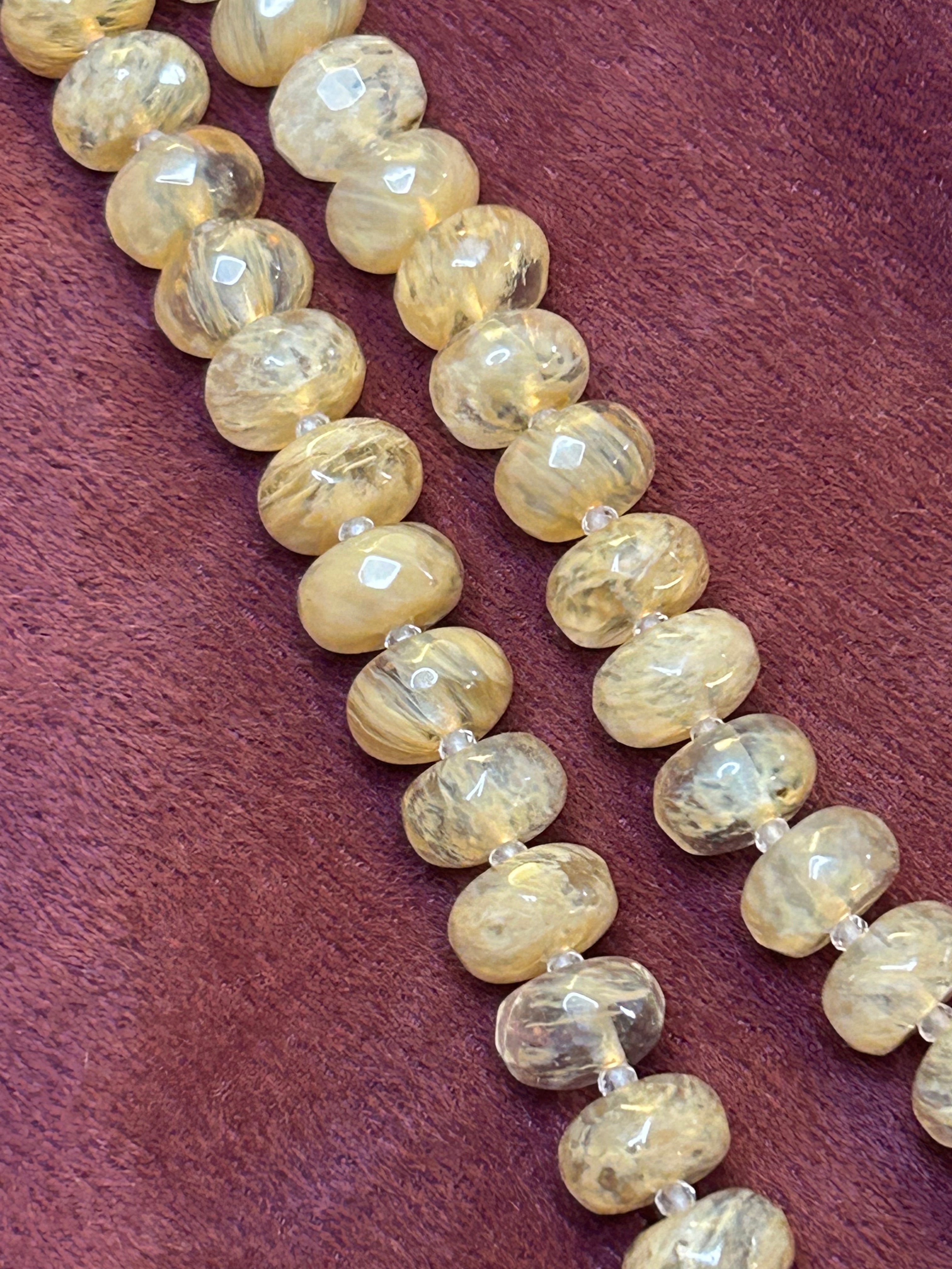 Necklace with light-colored beads on a maroon background