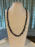 Black beaded necklace on a beige mannequin bust against a neutral background