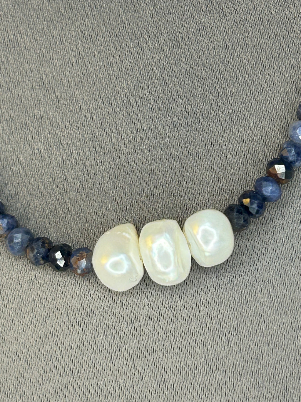 Necklace with pearls and dark blue beads on a gray surface