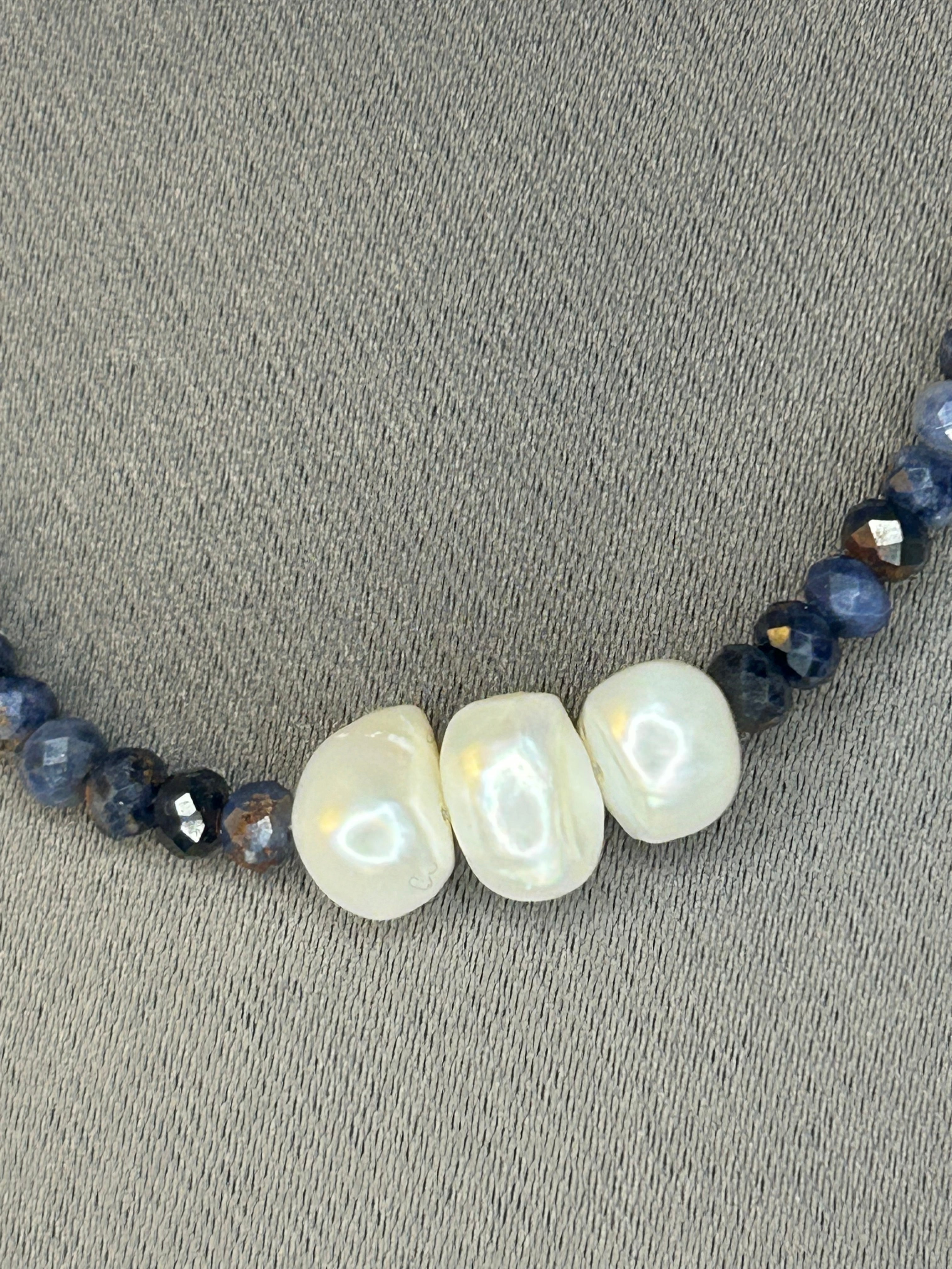 Necklace with pearls and dark blue beads on a gray surface