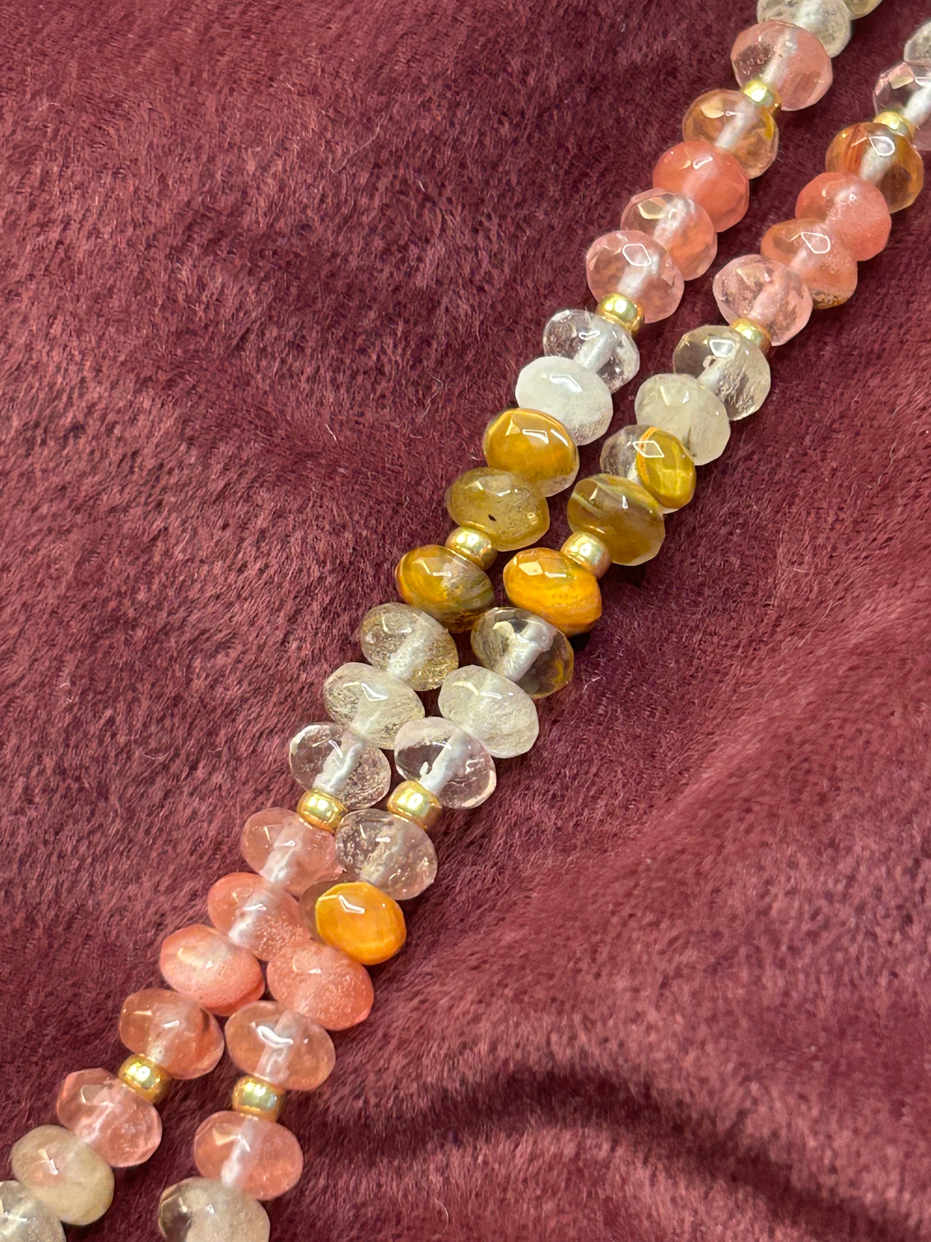 Necklace with multicolored beads on a textured purple fabric background