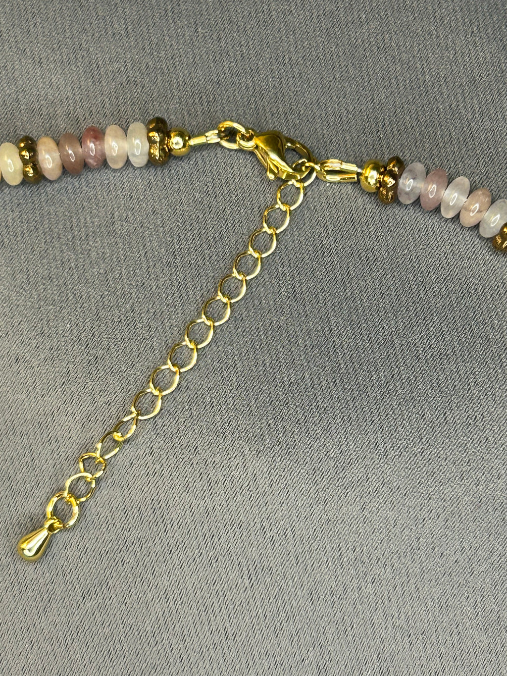 Beaded necklace with gold chain on a gray background
